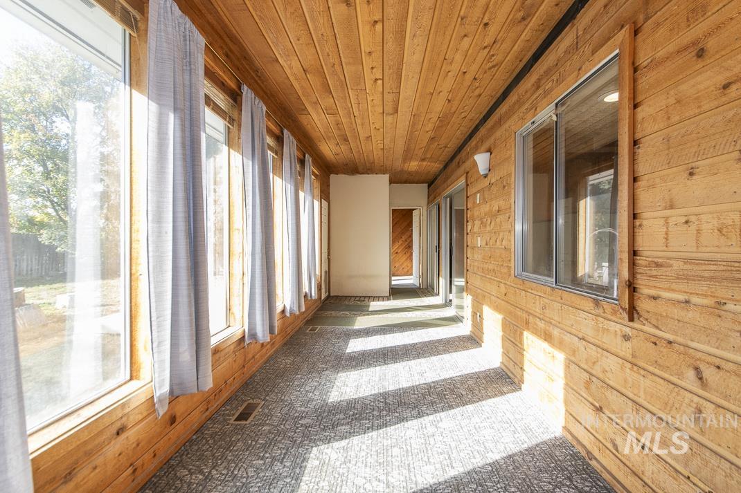Unfurnished sunroom featuring wood walls and wood ceiling