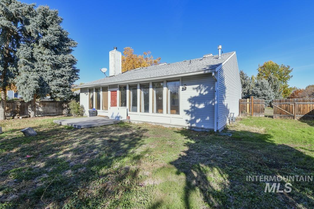 Back of house featuring a sunroom, a fenced backyard, a chimney, and a patio area