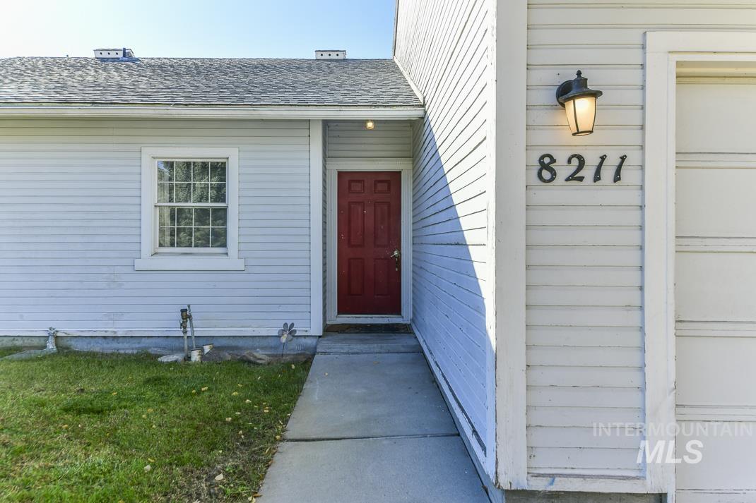 Doorway to property with roof with shingles and a lawn