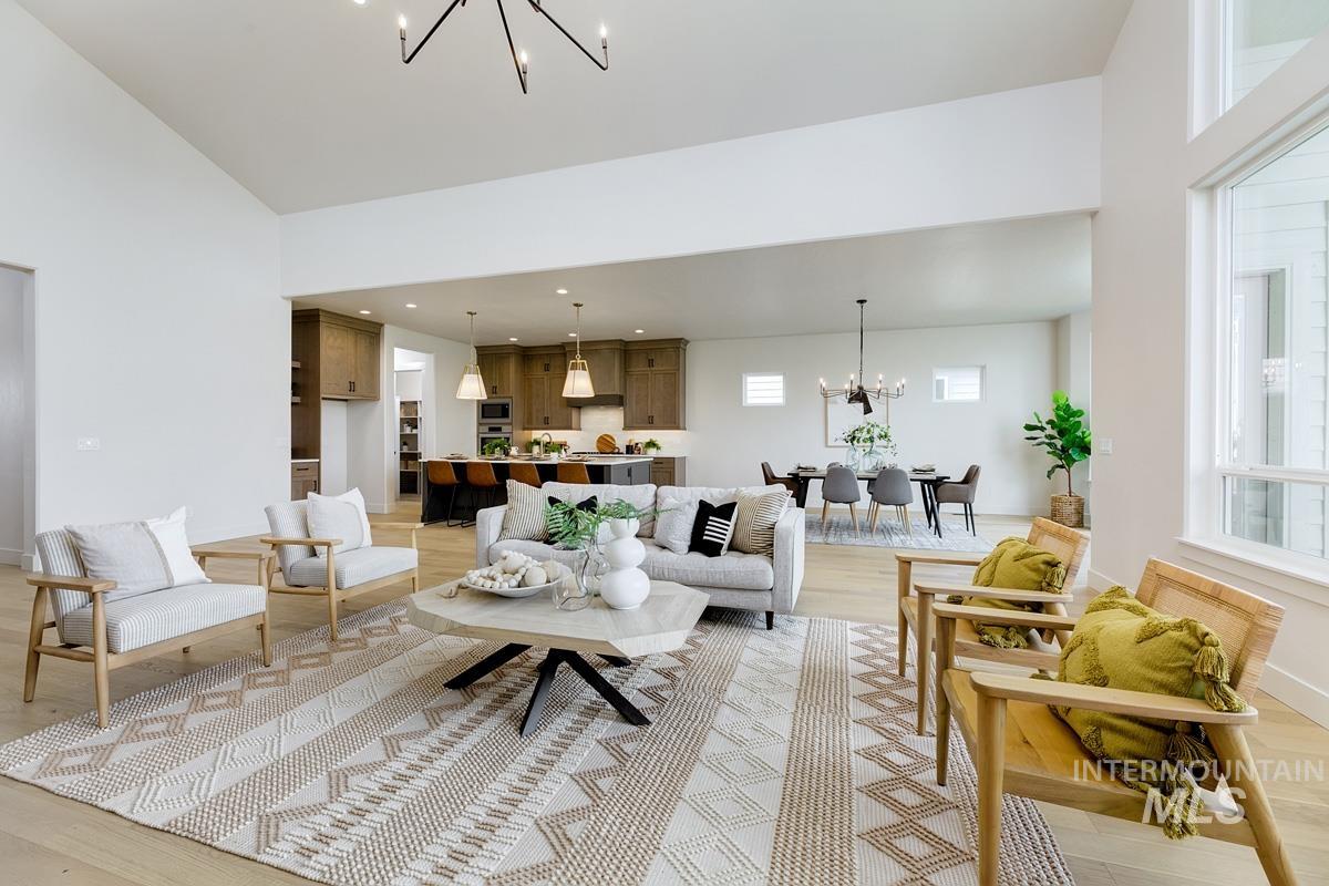 Living room with a chandelier, light wood finished floors, and a high ceiling