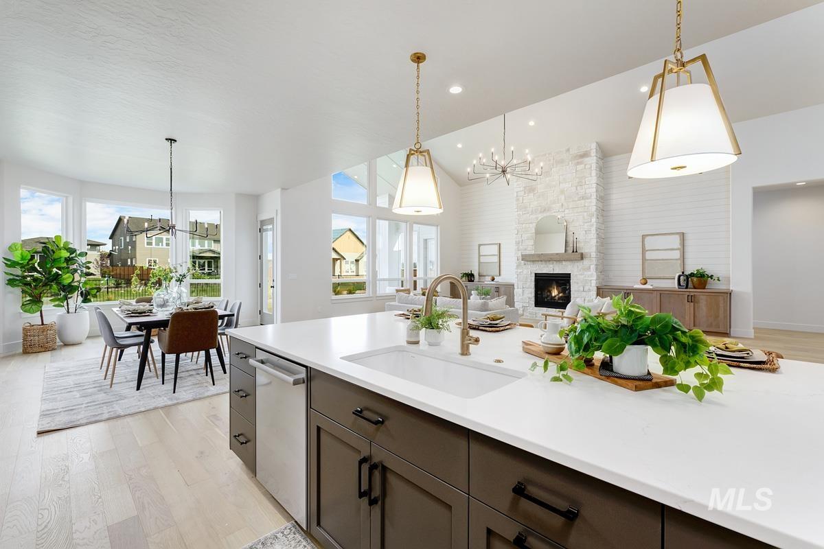 Kitchen featuring light wood-type flooring, a chandelier, lofted ceiling, a fireplace, and open floor plan