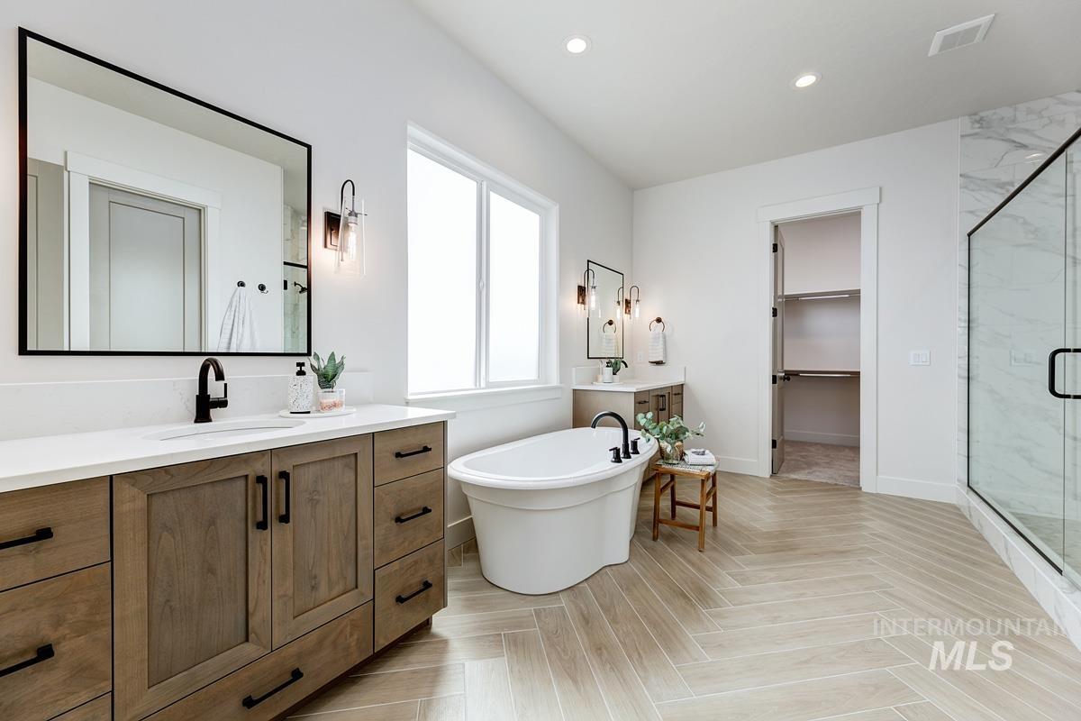Full bathroom featuring vanity, a walk in closet, a marble finish shower, parquet flooring, and recessed lighting