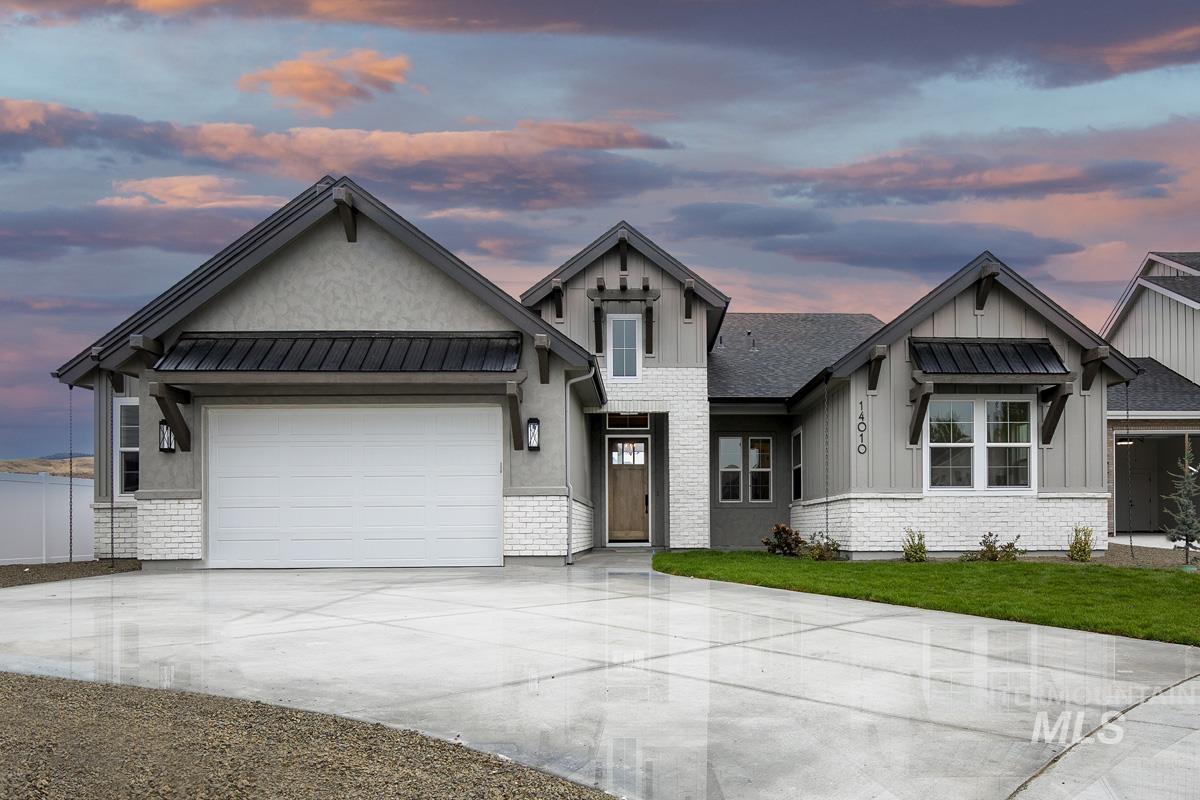 View of front of house featuring driveway, board and batten siding, an attached garage, and a standing seam roof