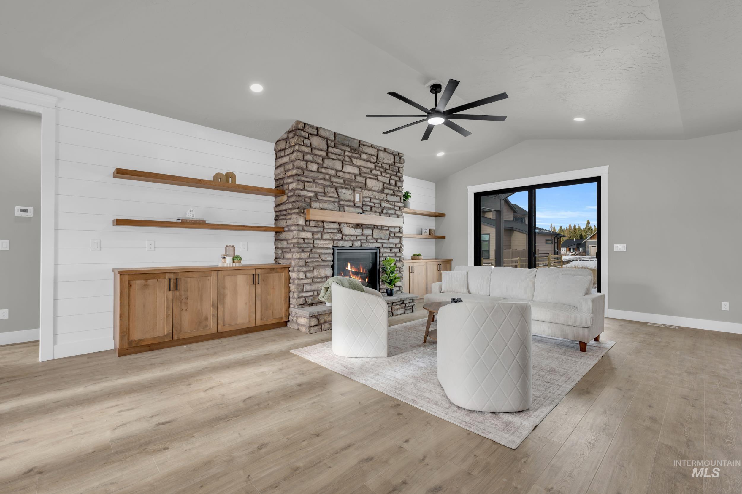 Living room with light wood finished floors, a fireplace, a ceiling fan, recessed lighting, and lofted ceiling