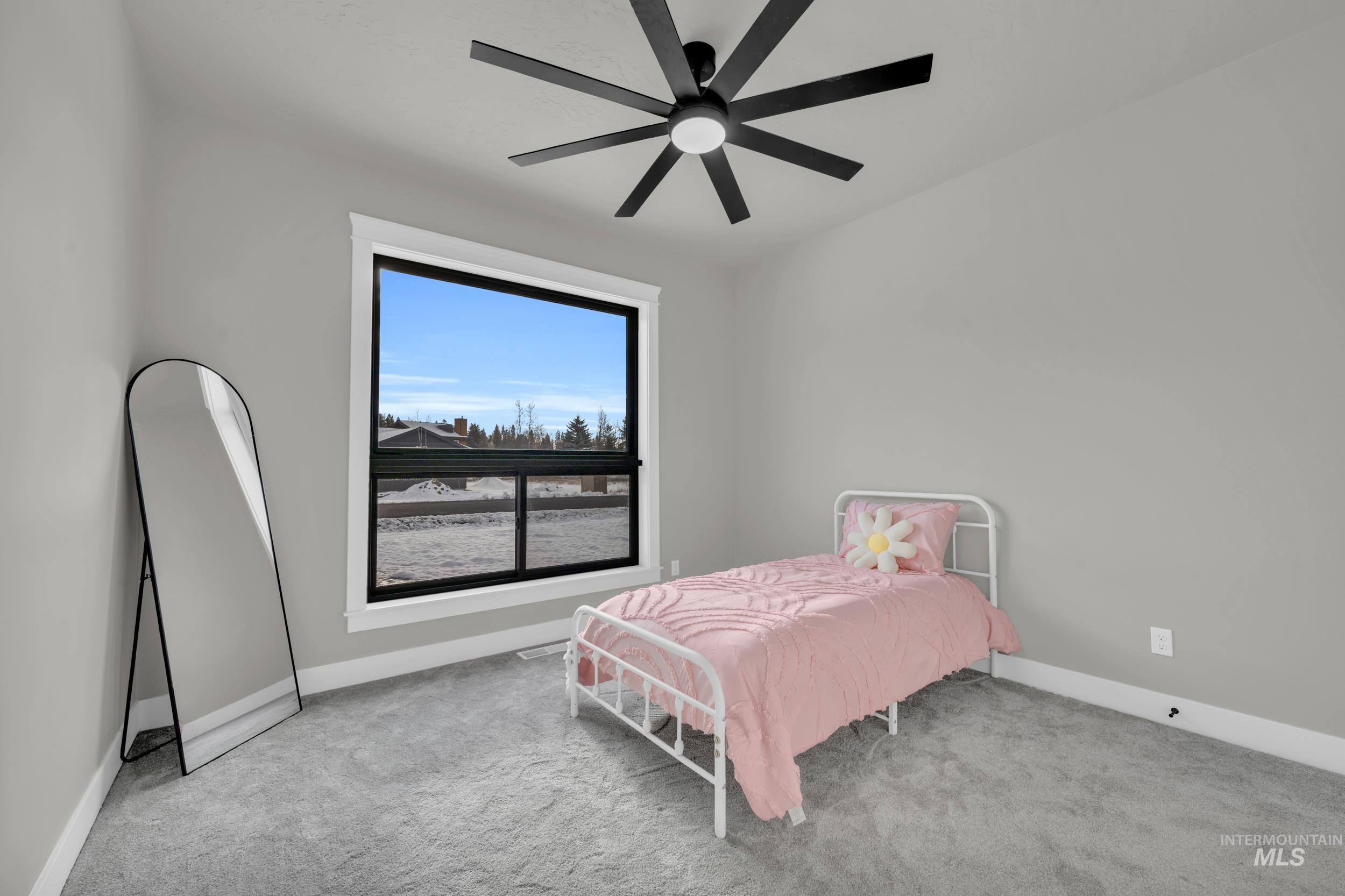 Carpeted bedroom featuring ceiling fan and baseboards