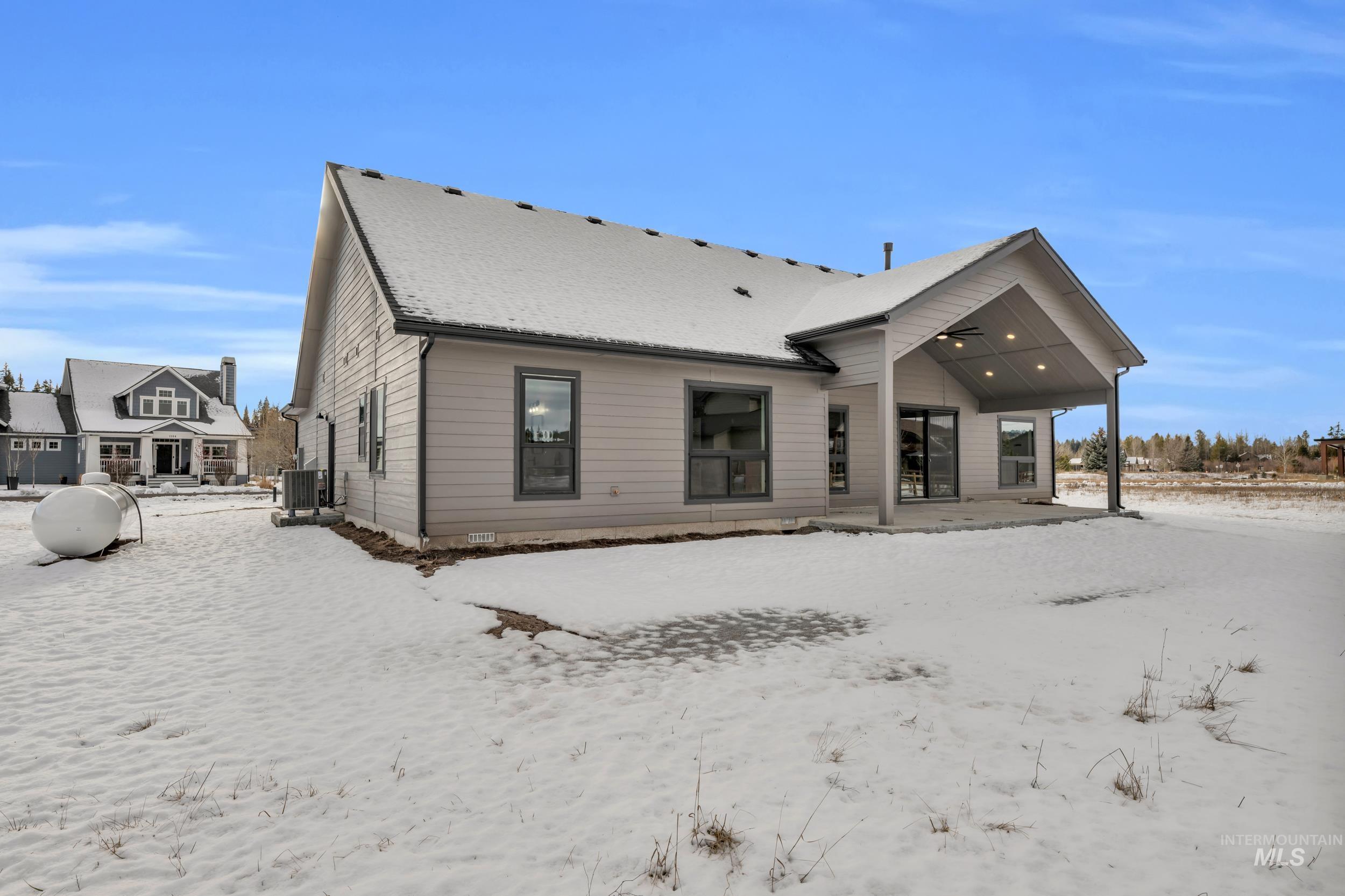 Snow covered back of property featuring a patio area