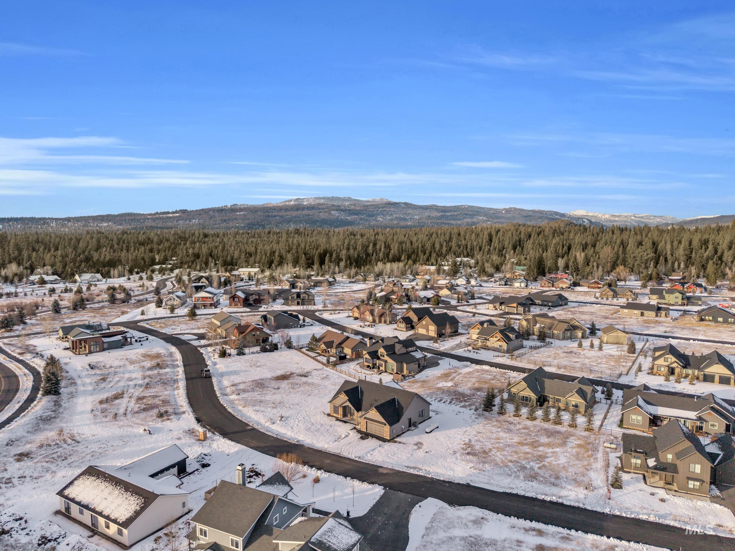 Snowy aerial view with a residential view, a mountain view, and a wooded view