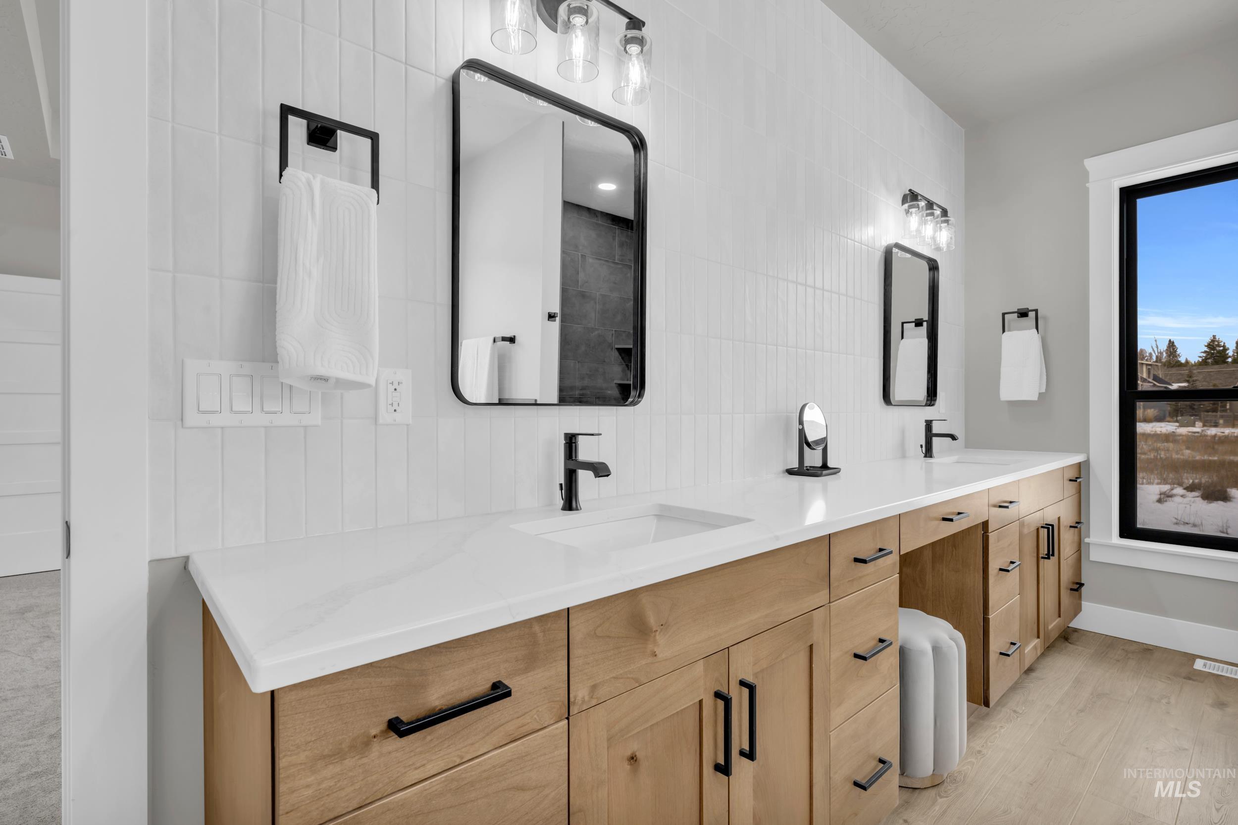 Full bath featuring tile walls, double vanity, and light wood finished floors