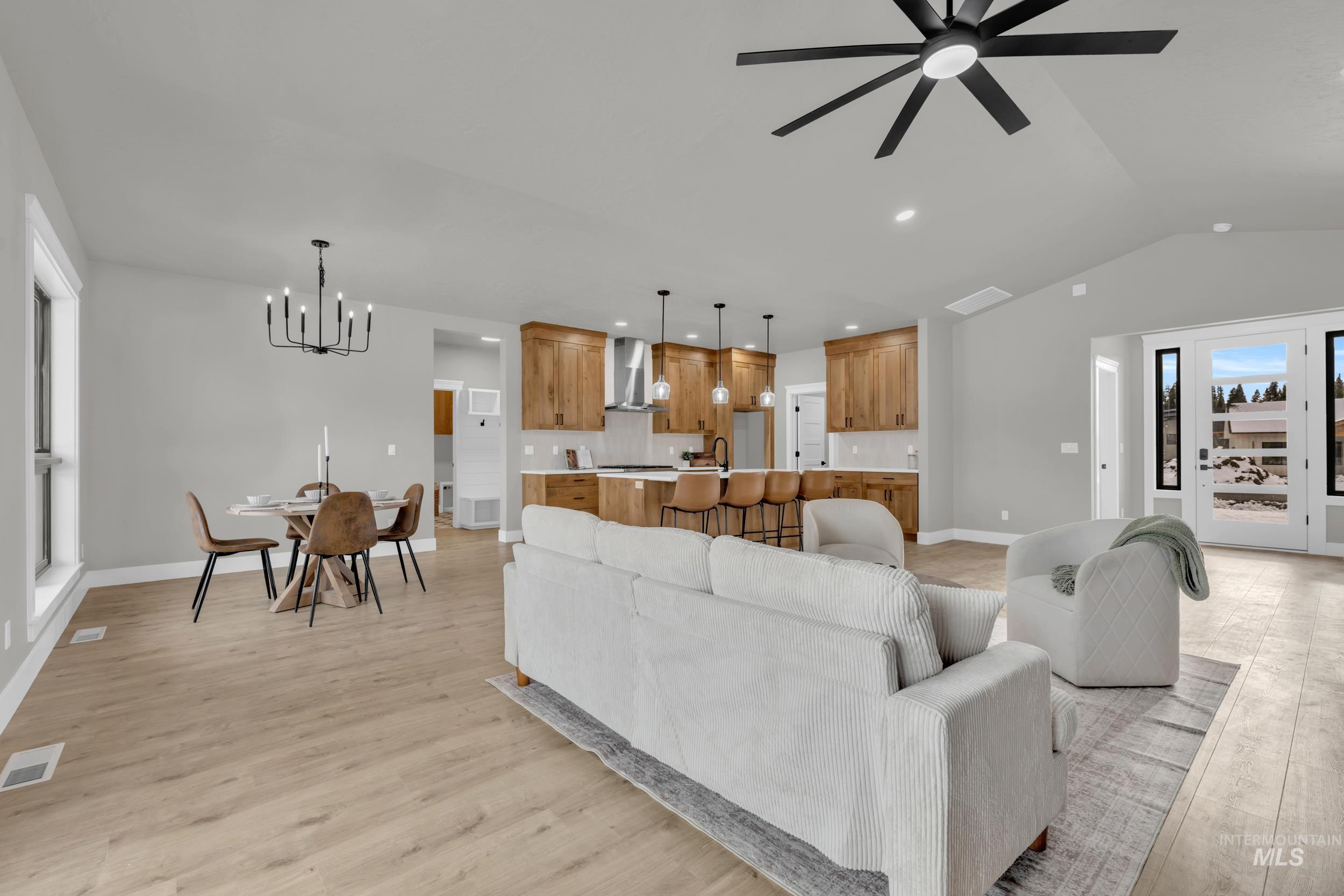 Living room with a chandelier, a ceiling fan, lofted ceiling, light wood finished floors, and recessed lighting