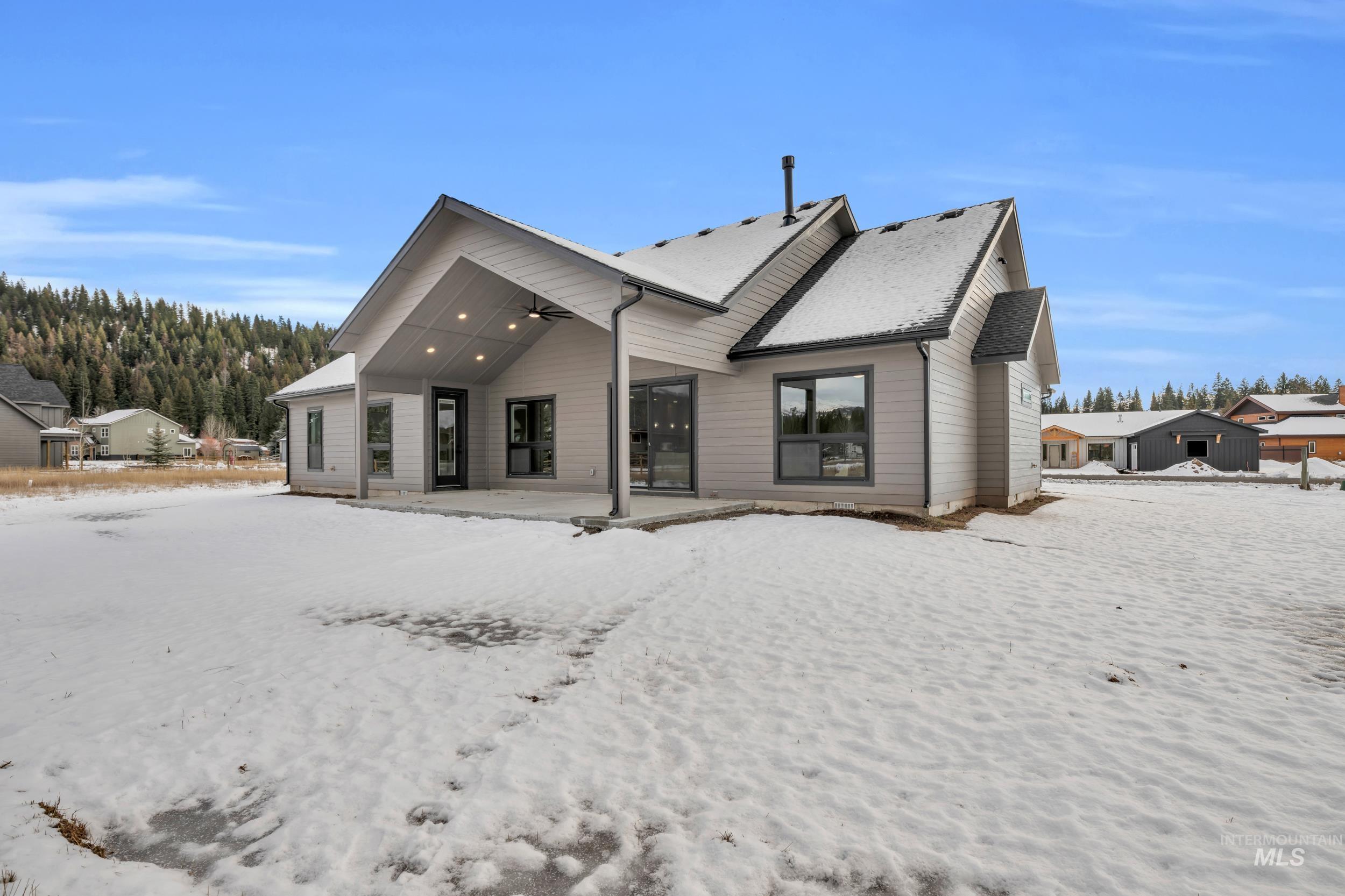 Snow covered back of property featuring a patio and ceiling fan