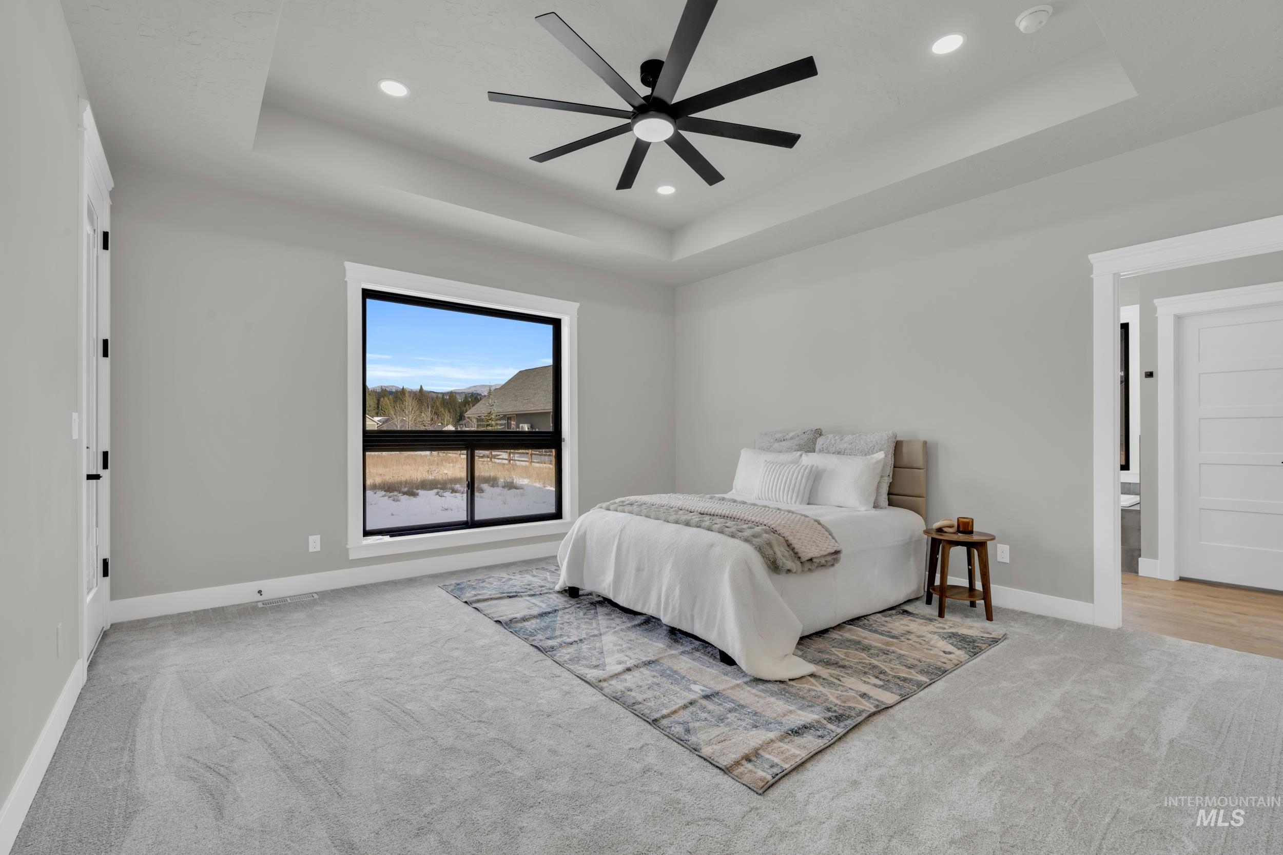 Bedroom featuring a raised ceiling, light colored carpet, ceiling fan, and recessed lighting
