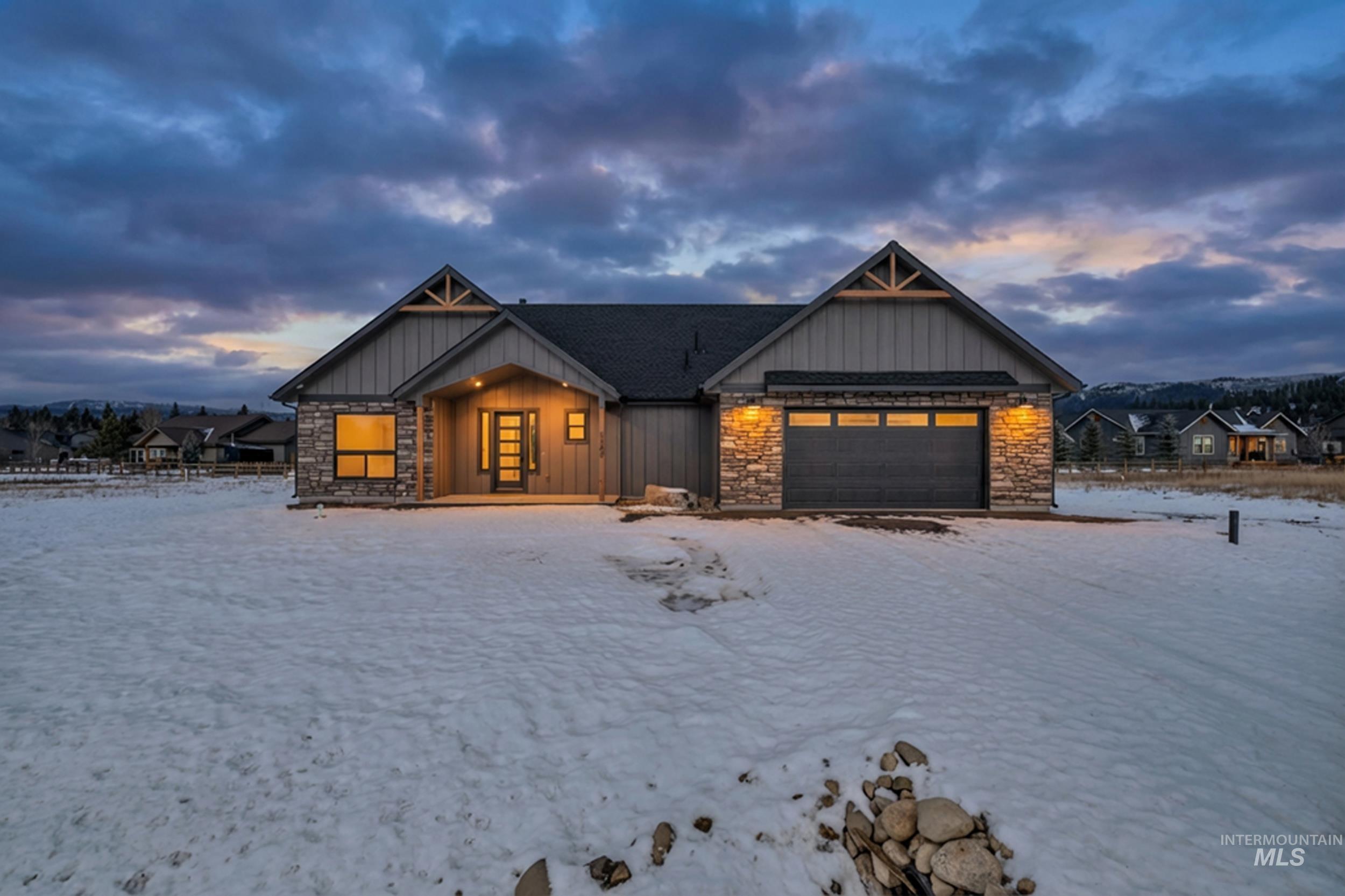 Modern inspired farmhouse with board and batten siding, stone siding, and a garage