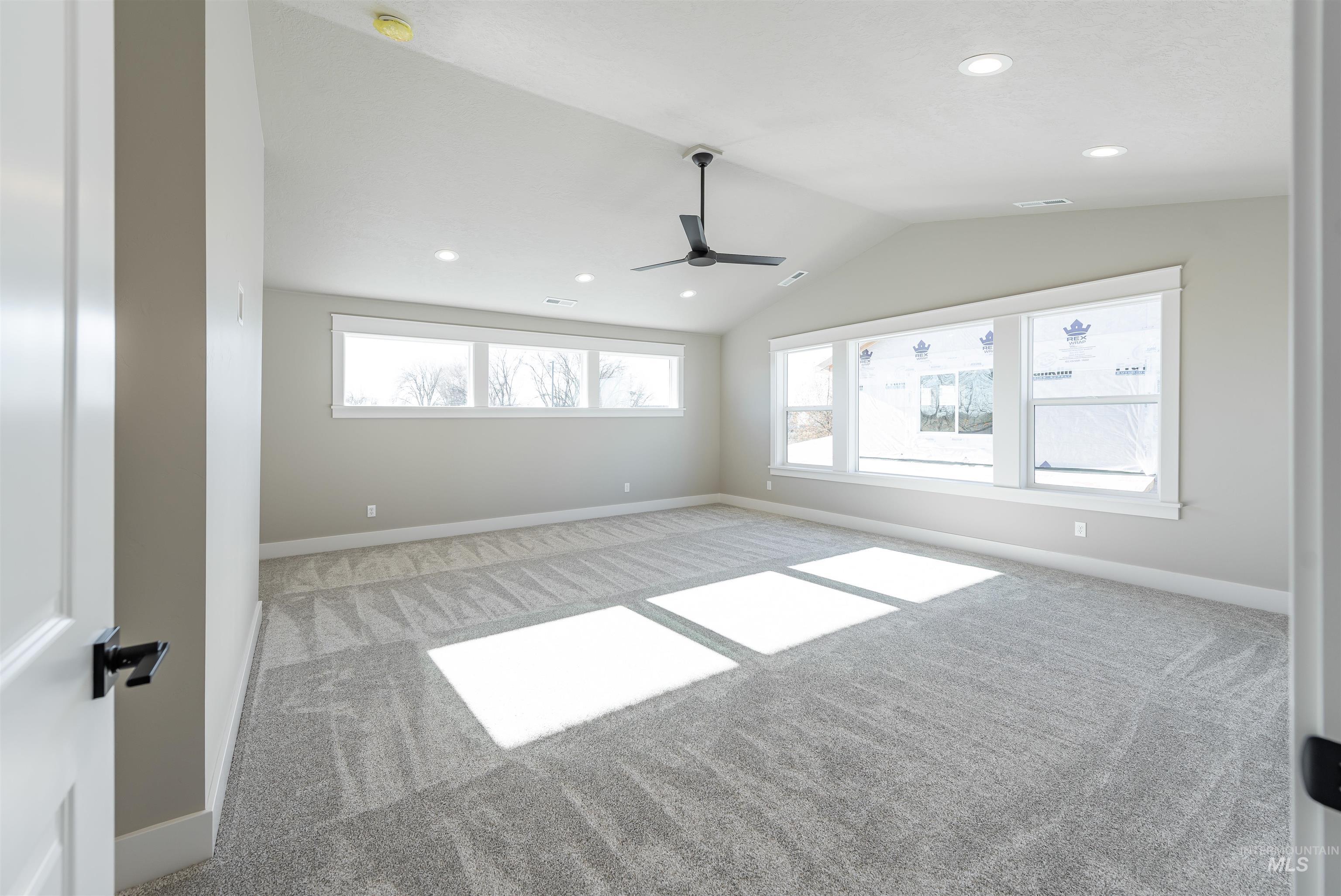 Carpeted empty room featuring vaulted ceiling, recessed lighting, and a ceiling fan
