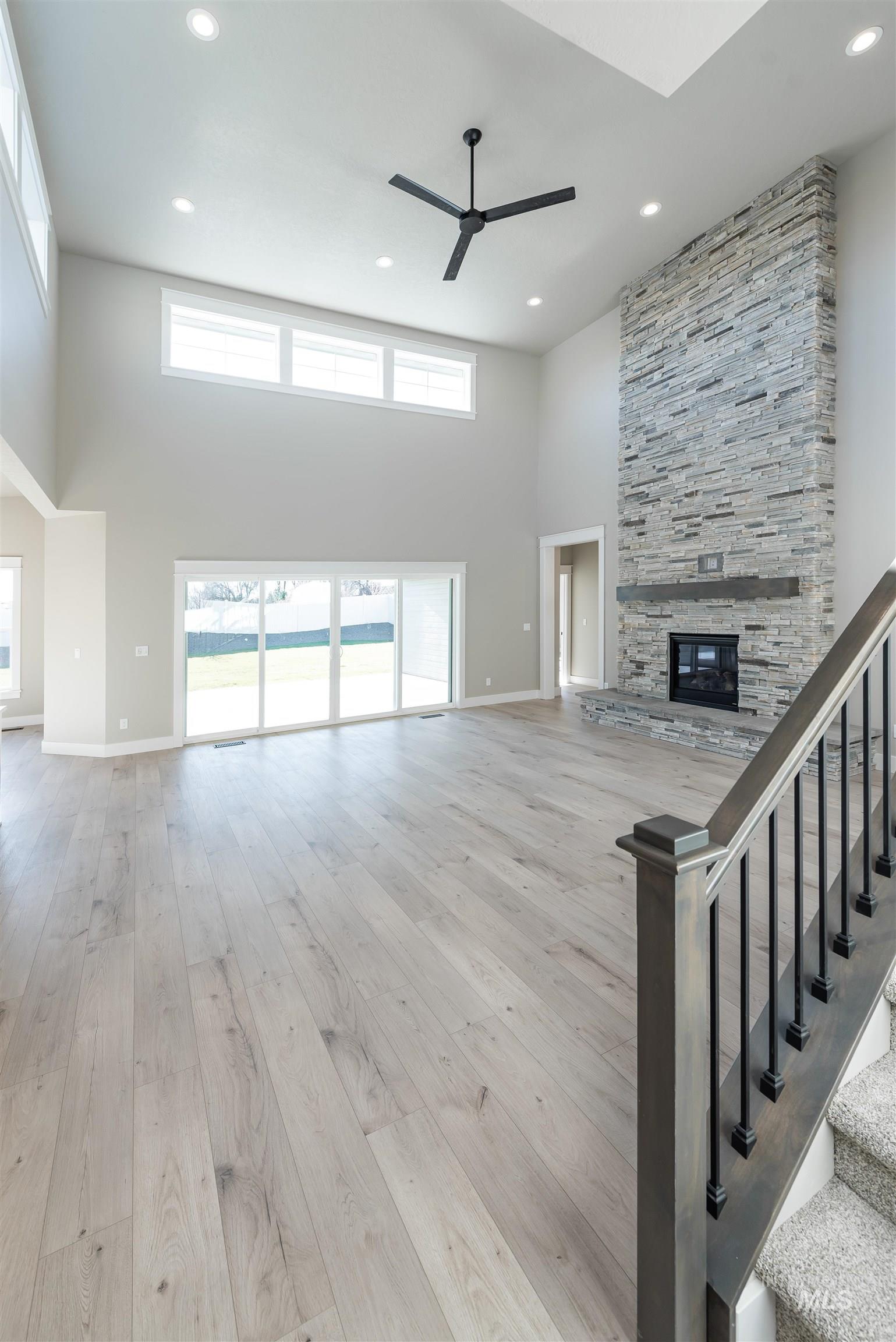 Unfurnished living room with a high ceiling, a fireplace, light wood-style floors, recessed lighting, and ceiling fan