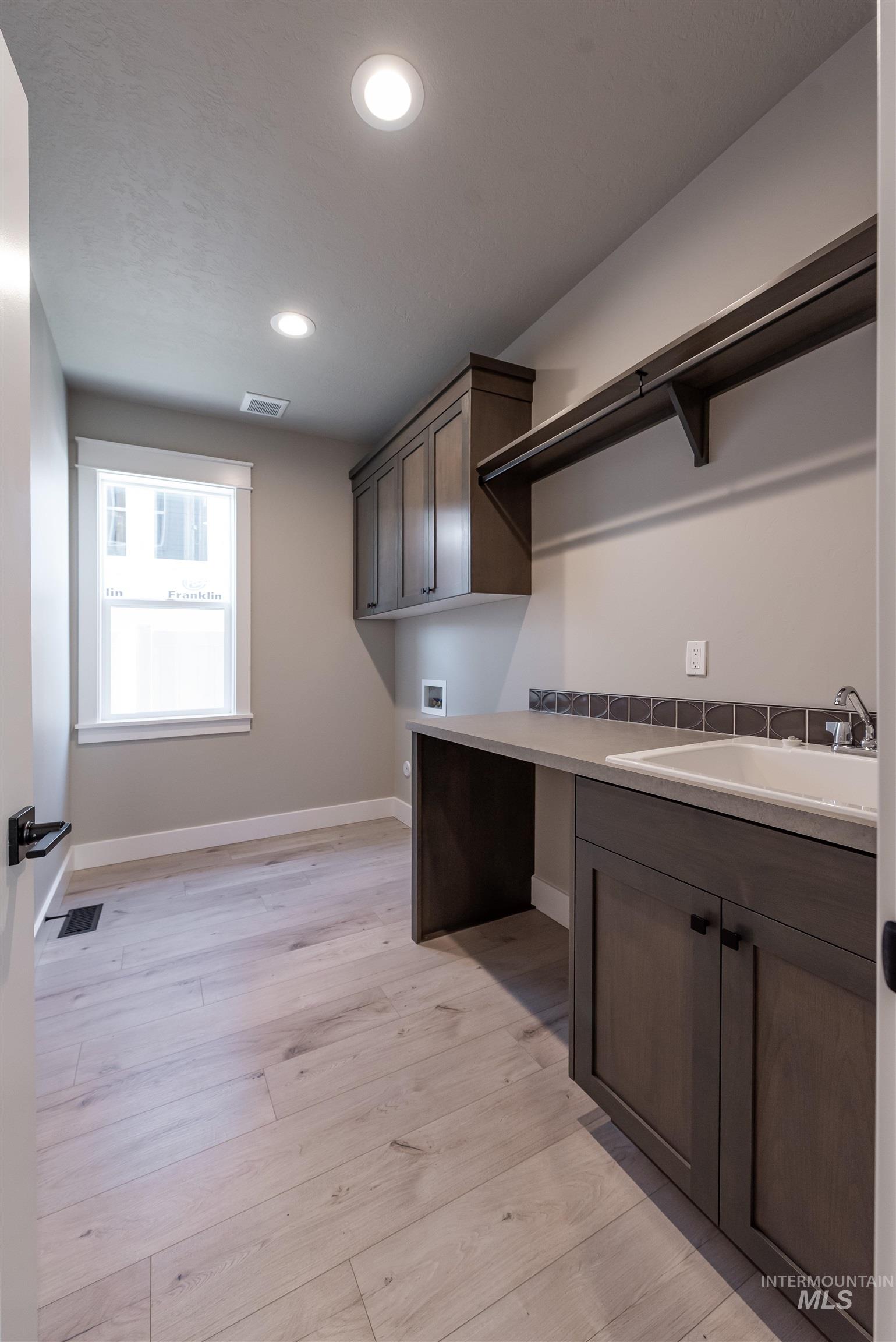 Washroom featuring cabinet space, hookup for a washing machine, light wood-style floors, and recessed lighting