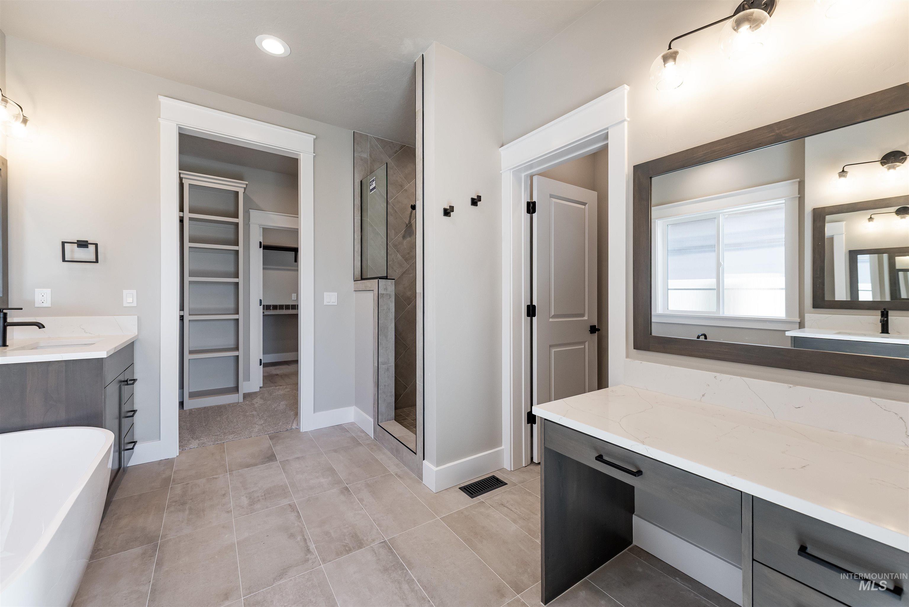 Full bath featuring vanity, a spacious closet, a soaking tub, a shower stall, and recessed lighting