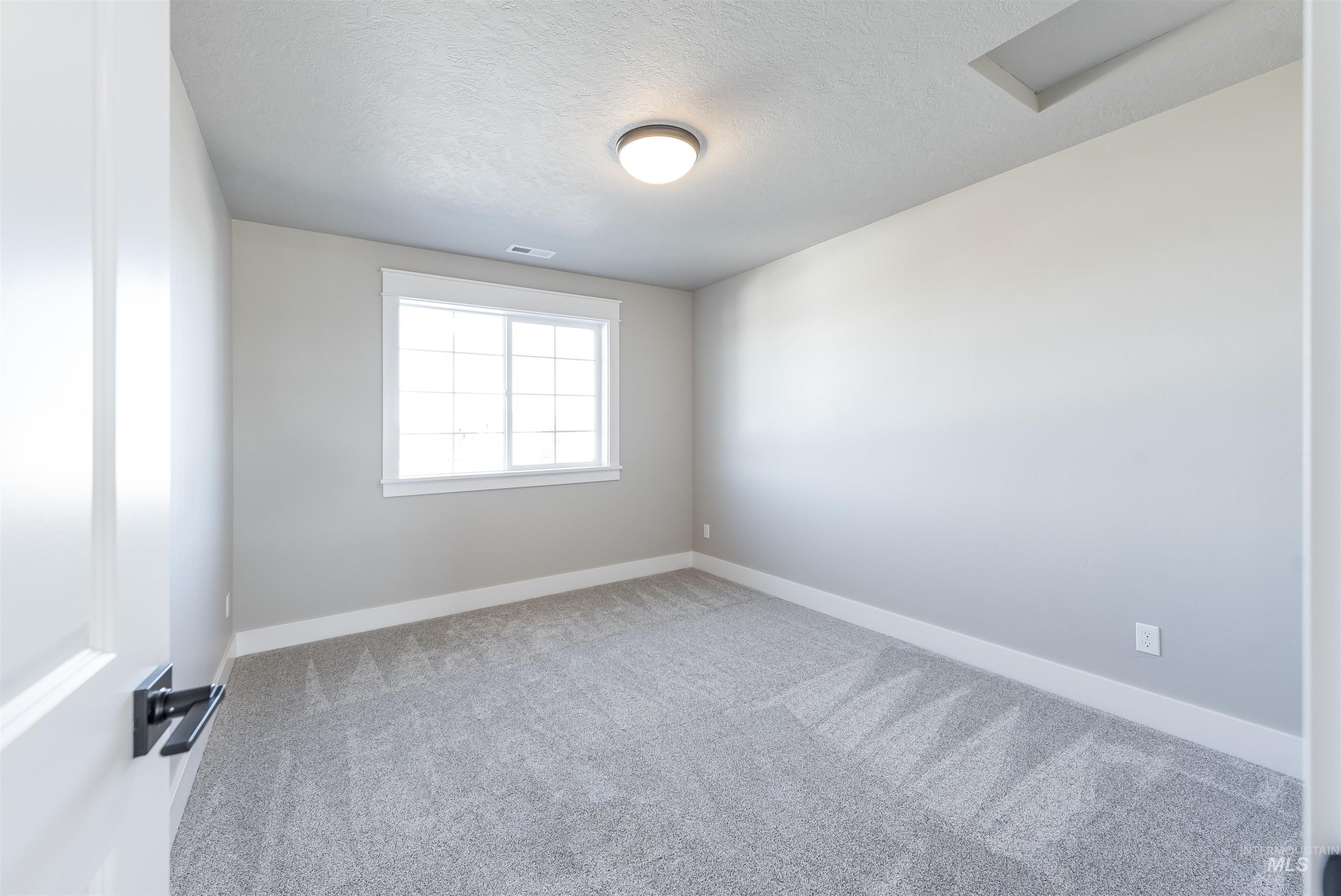 Unfurnished room featuring a textured ceiling and carpet