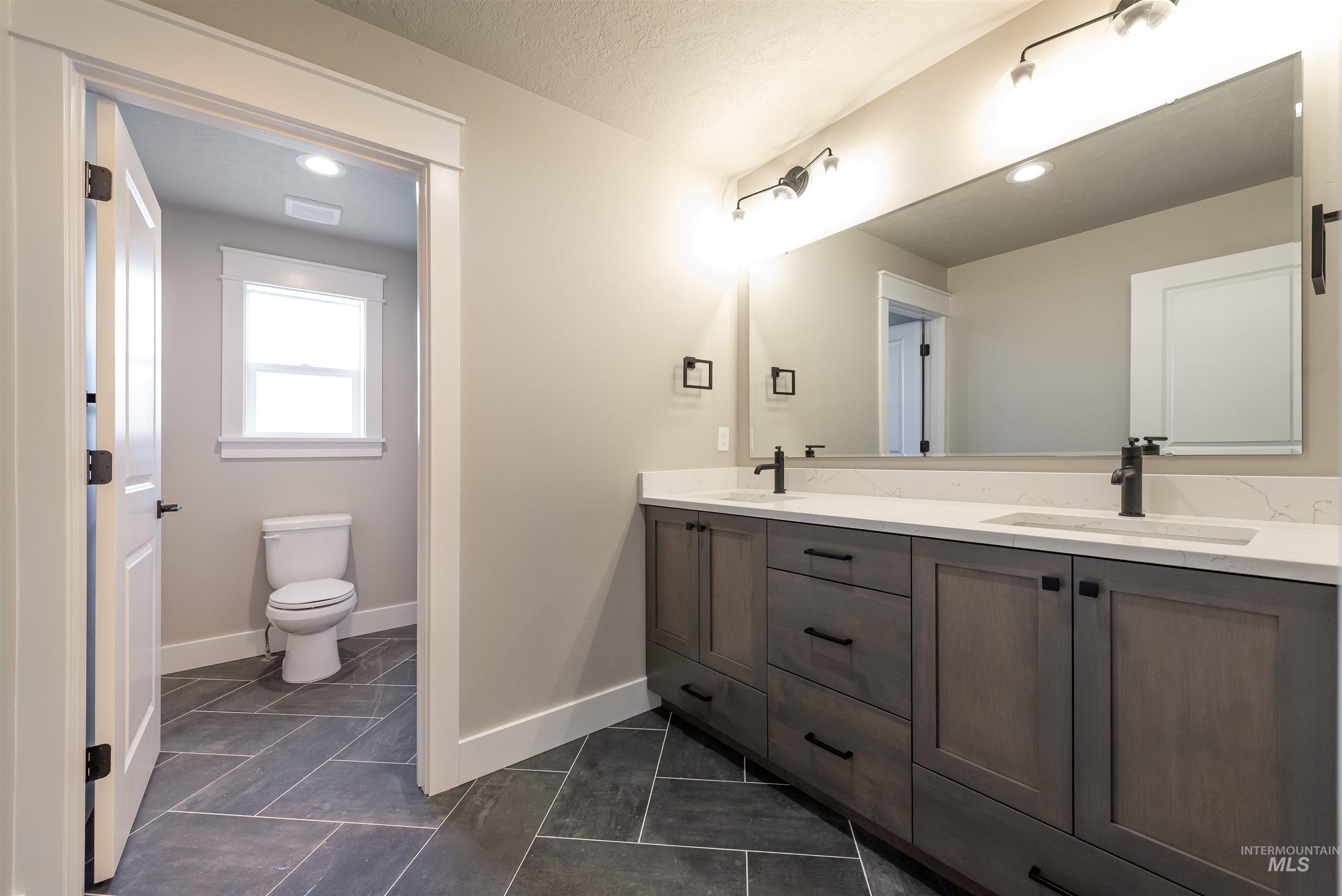 Full bath featuring double vanity, recessed lighting, and a textured ceiling