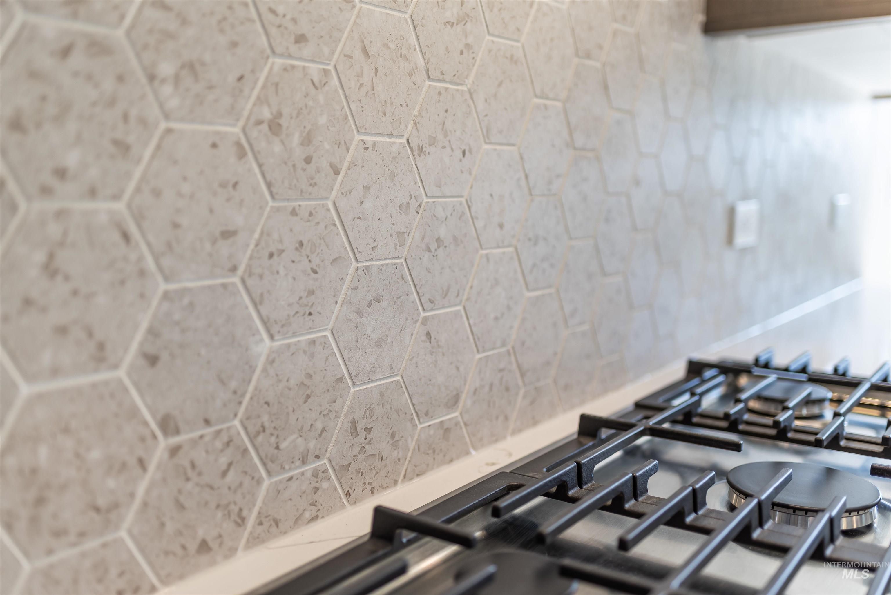 Kitchen view of stainless steel gas cooktop, light stone countertops, and pot filler