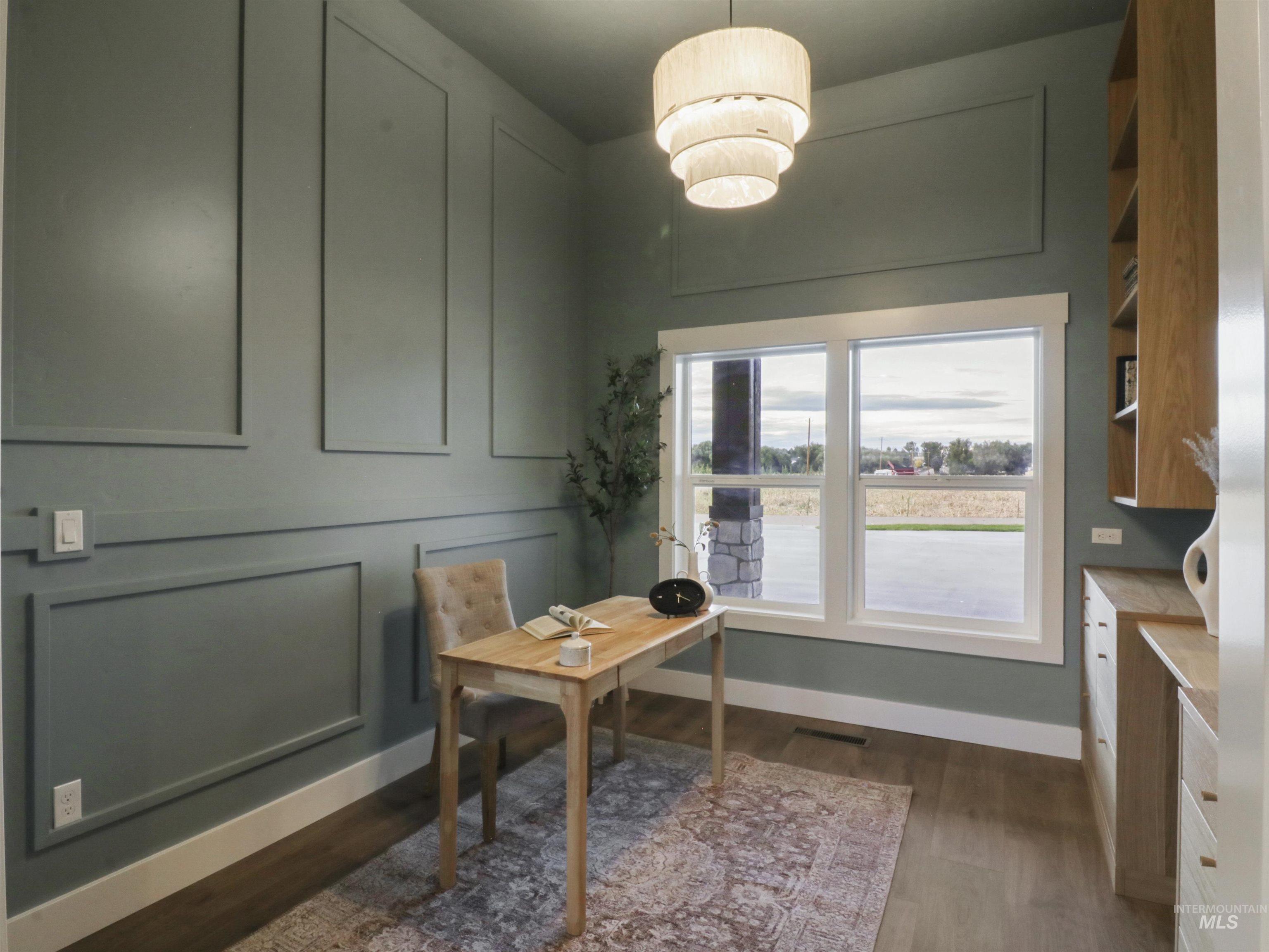 Home office with dark wood-style floors and a decorative wall