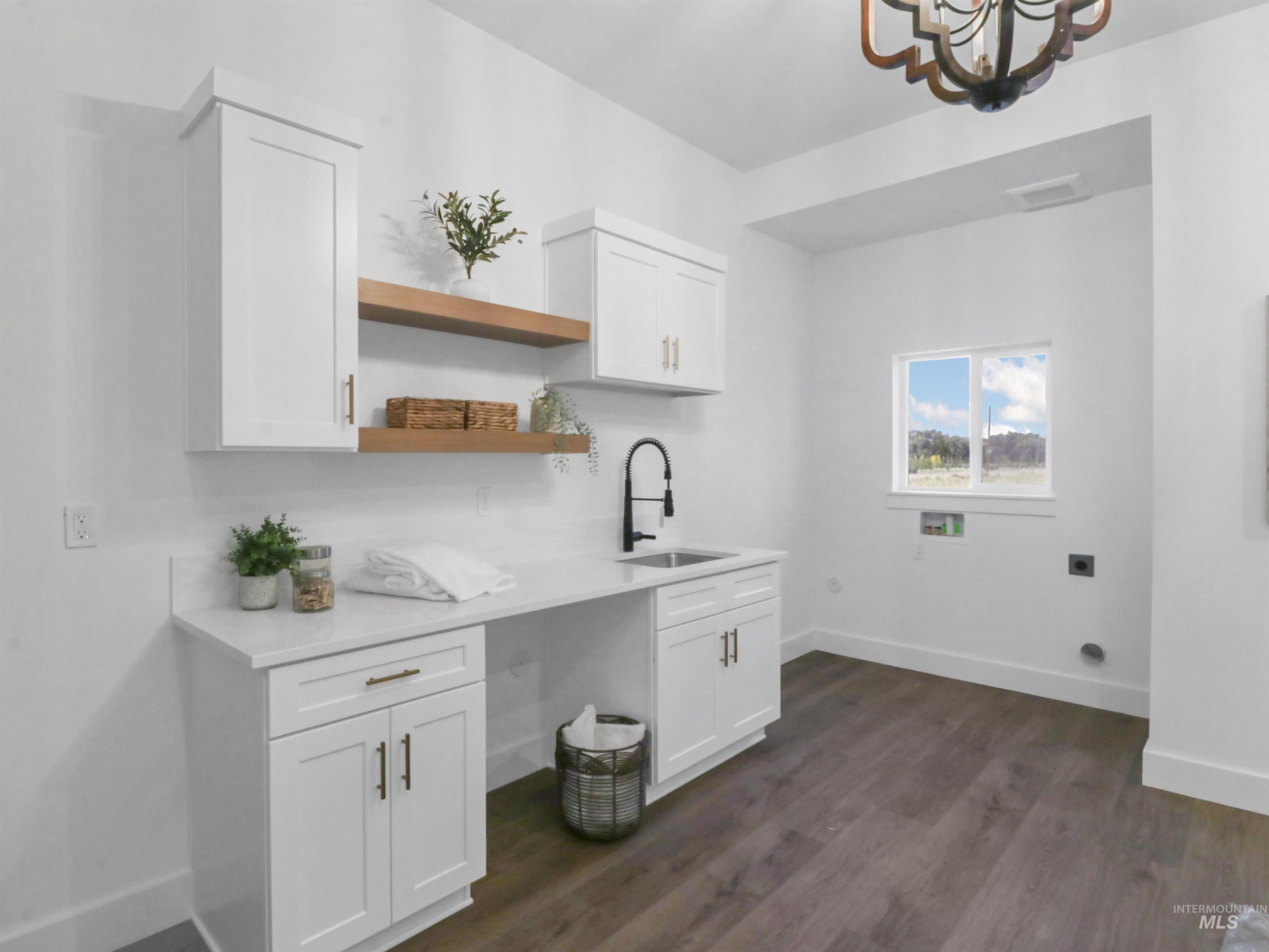 Washroom featuring dark wood-type flooring, a chandelier, washer hookup, cabinet space, and hookup for an electric dryer