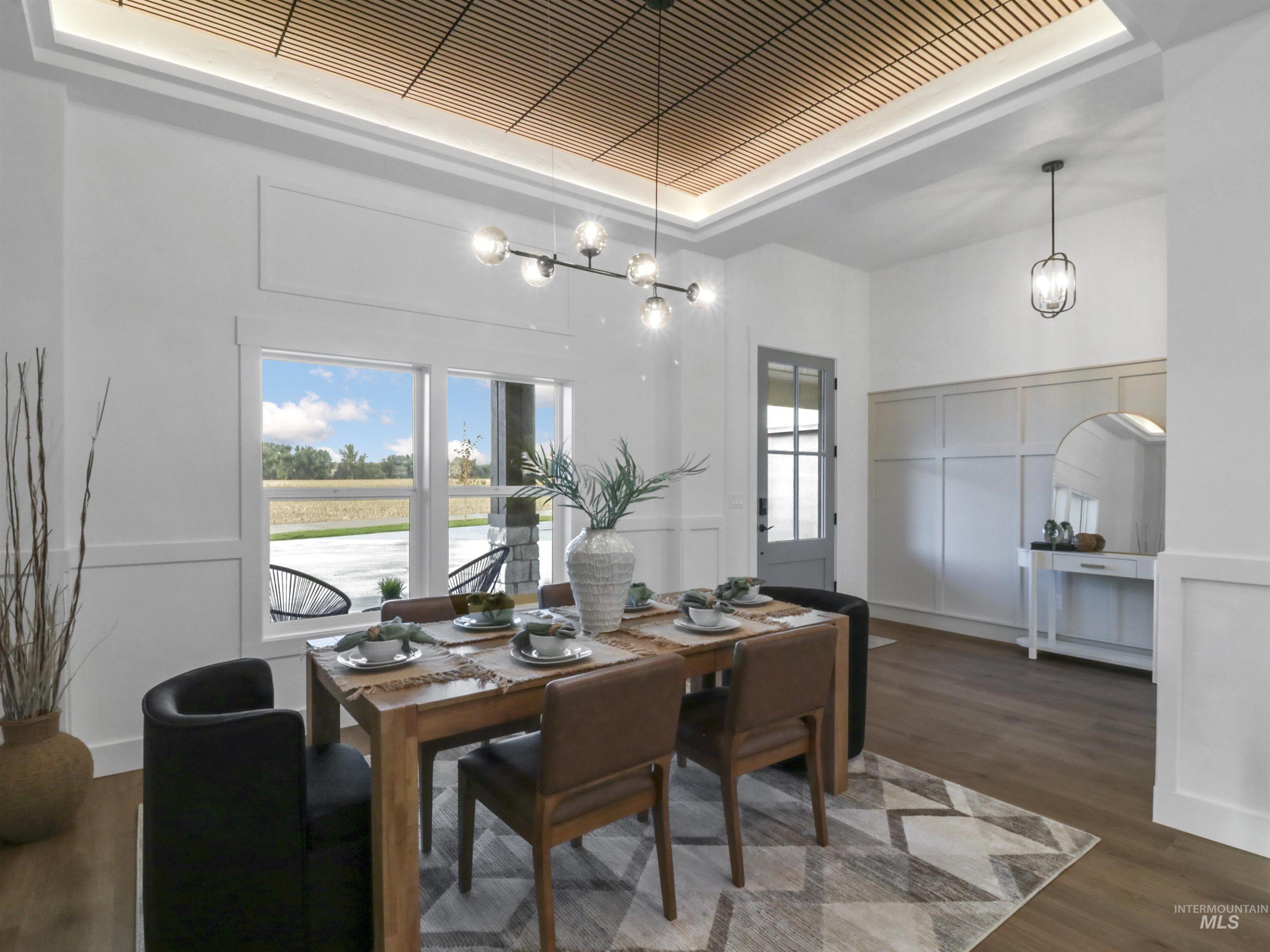 Dining space featuring a decorative wall, dark wood-style flooring, a chandelier, and a raised ceiling