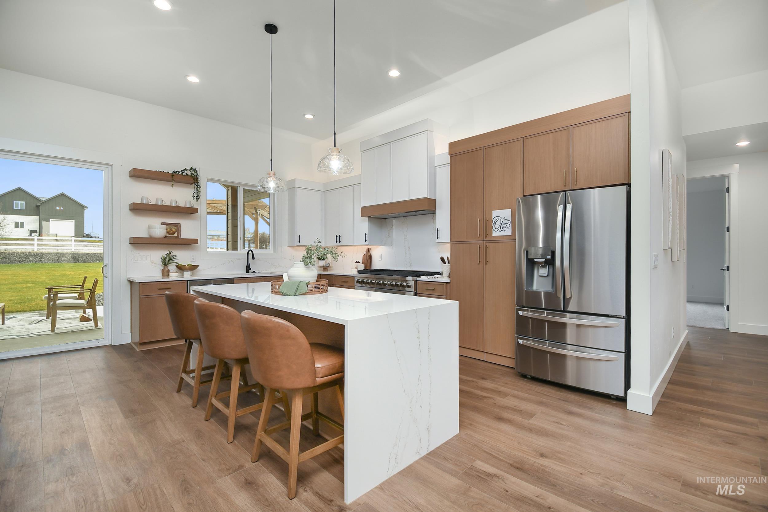 Kitchen featuring a kitchen bar, appliances with stainless steel finishes, decorative light fixtures, white cabinets, and a kitchen island