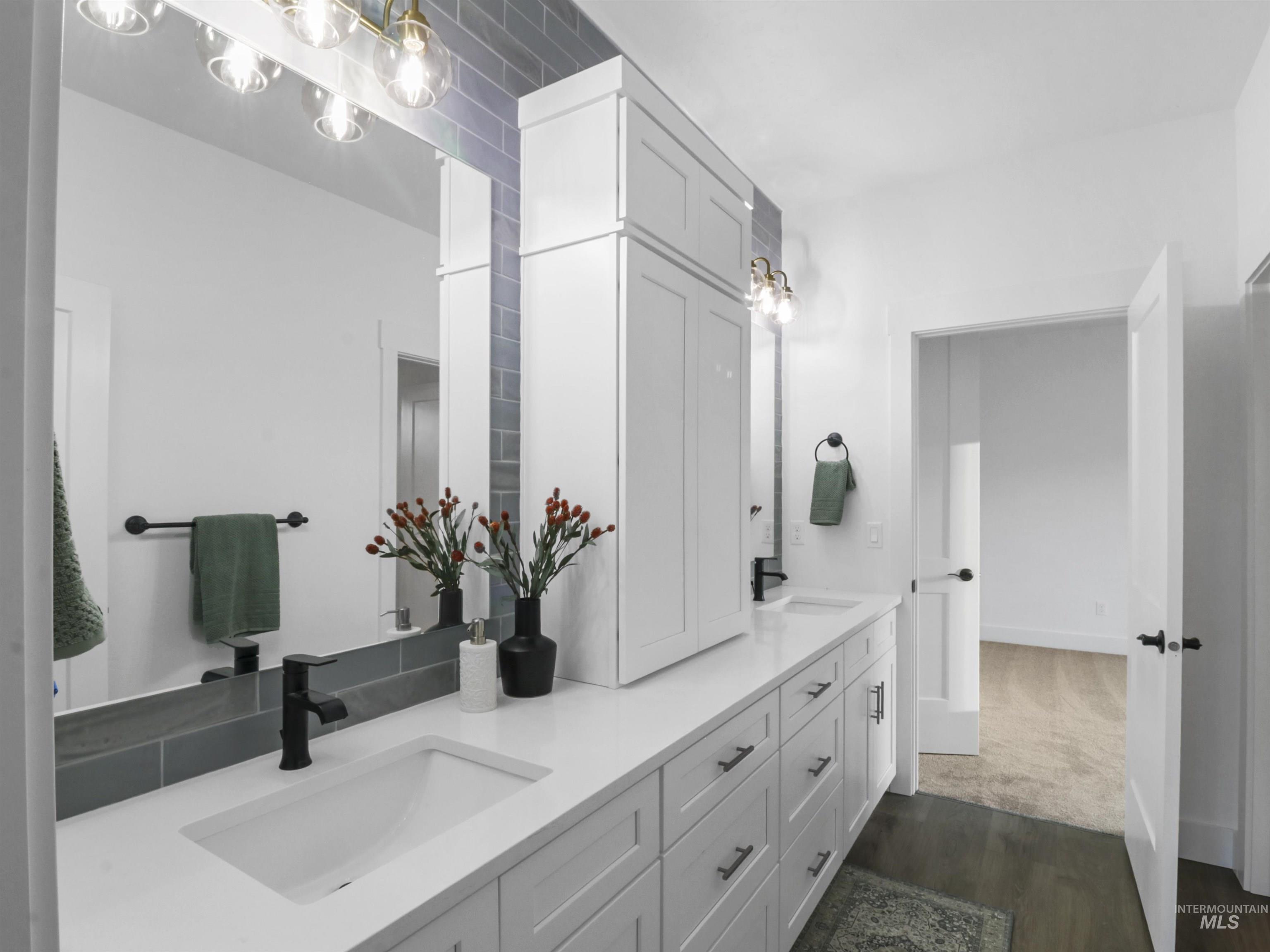 Full bath featuring double vanity and dark wood-type flooring