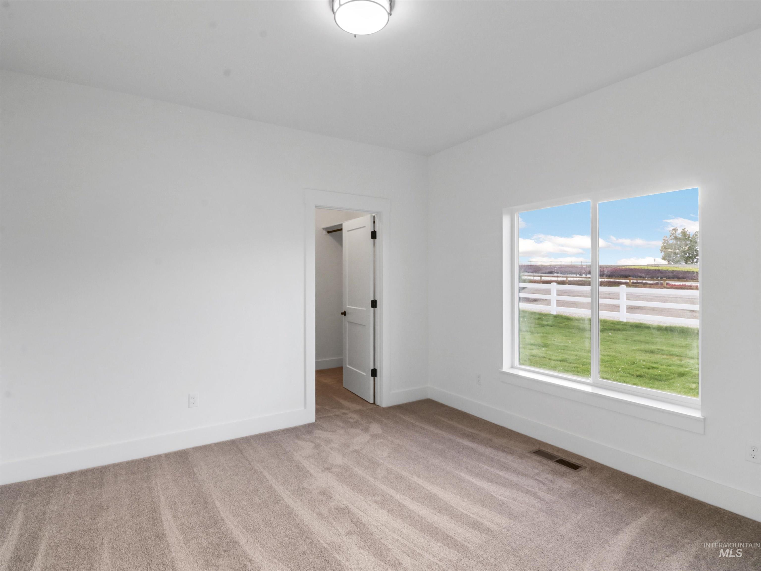 Unfurnished room featuring light carpet and baseboards