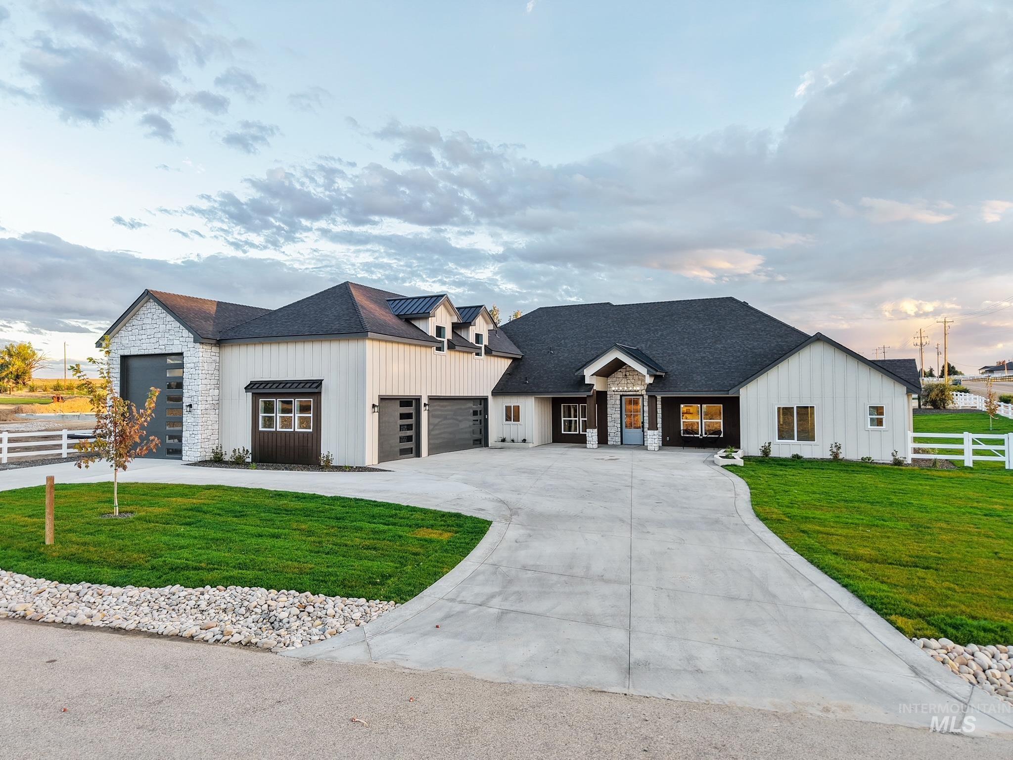 Modern inspired farmhouse with board and batten siding, stone siding, a shingled roof, concrete driveway, and a garage