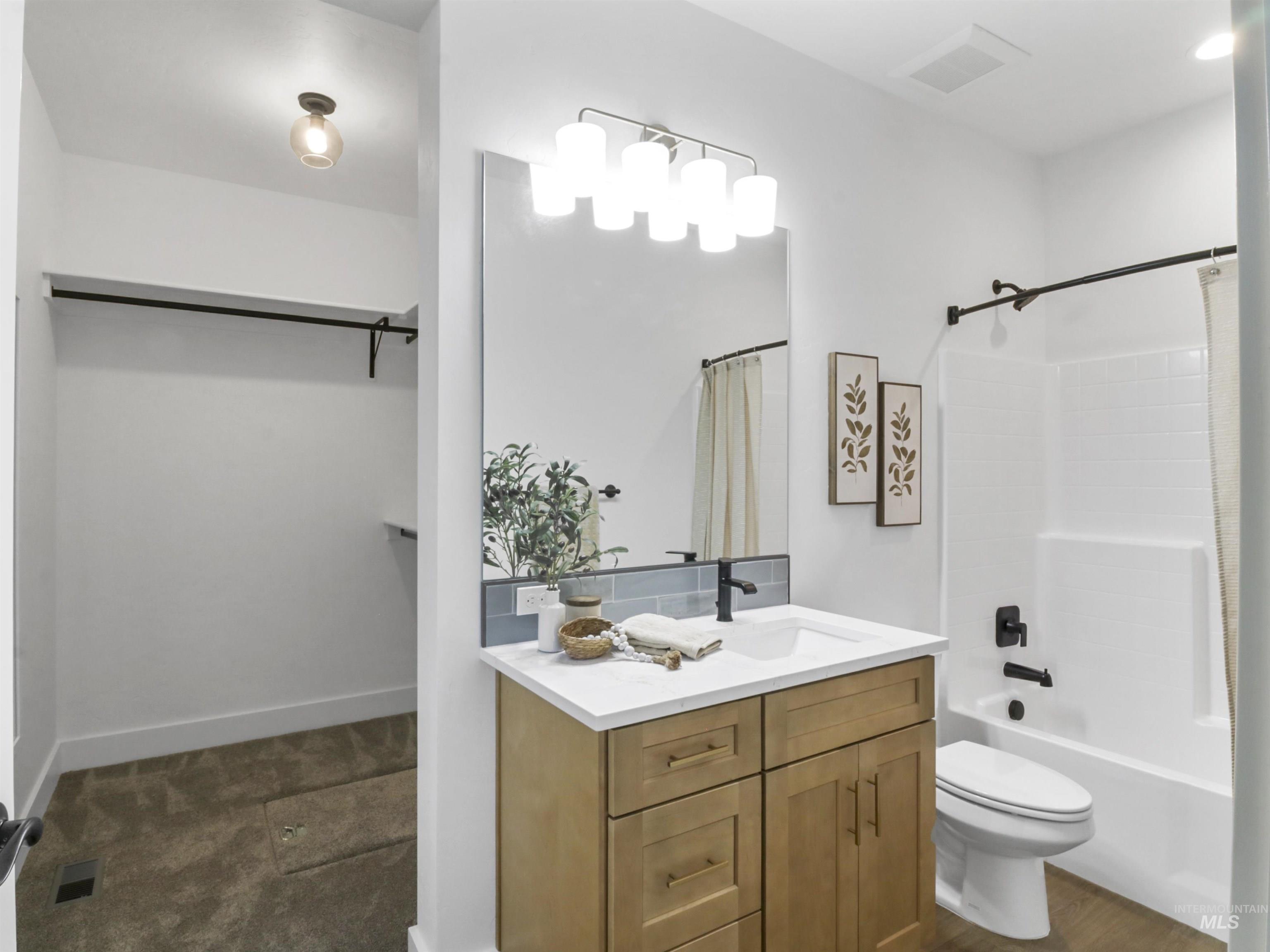 Bathroom featuring shower / bath combo with shower curtain, vanity, and a spacious closet