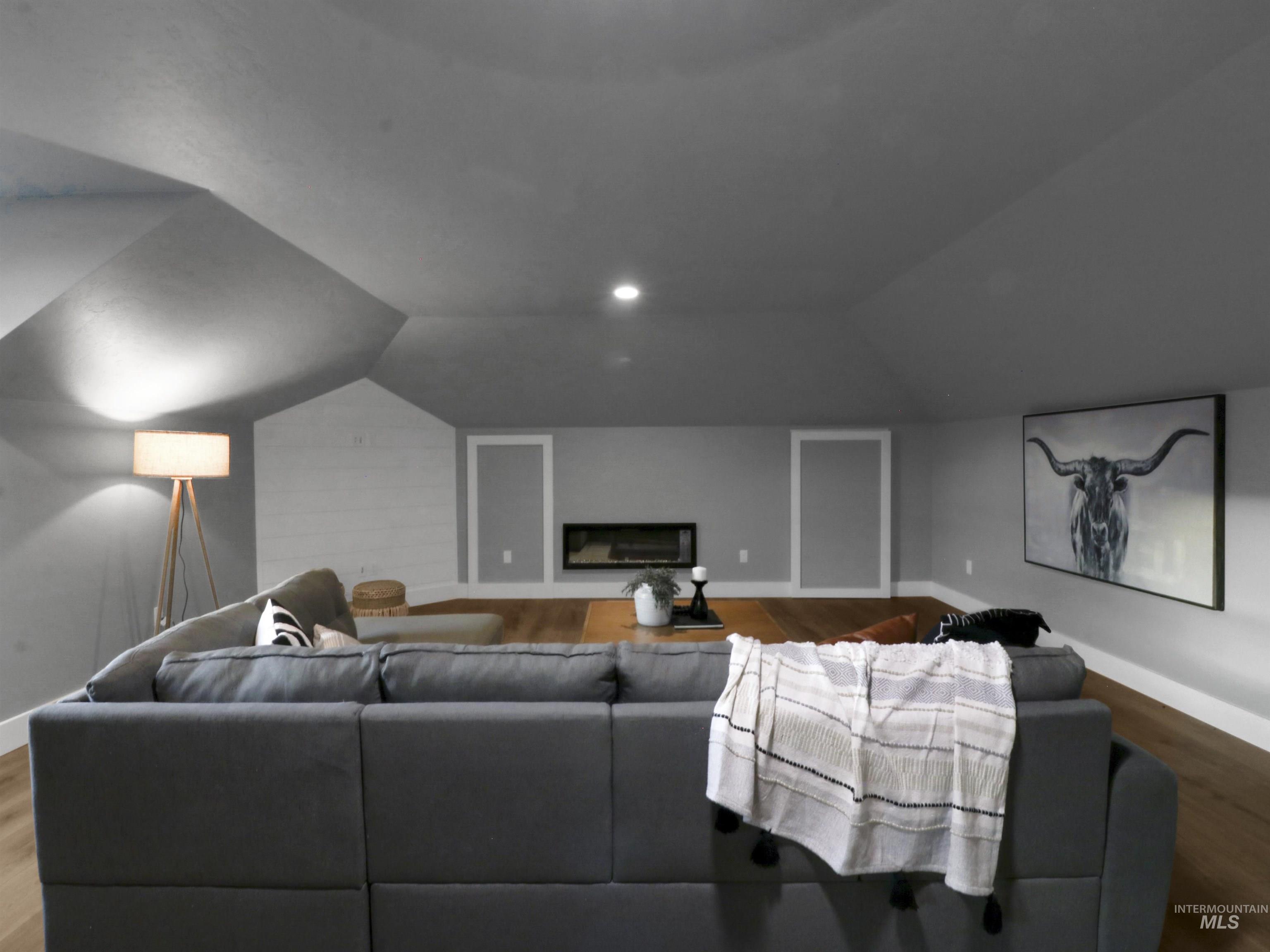 Cinema room featuring wood finished floors, lofted ceiling, and a glass covered fireplace