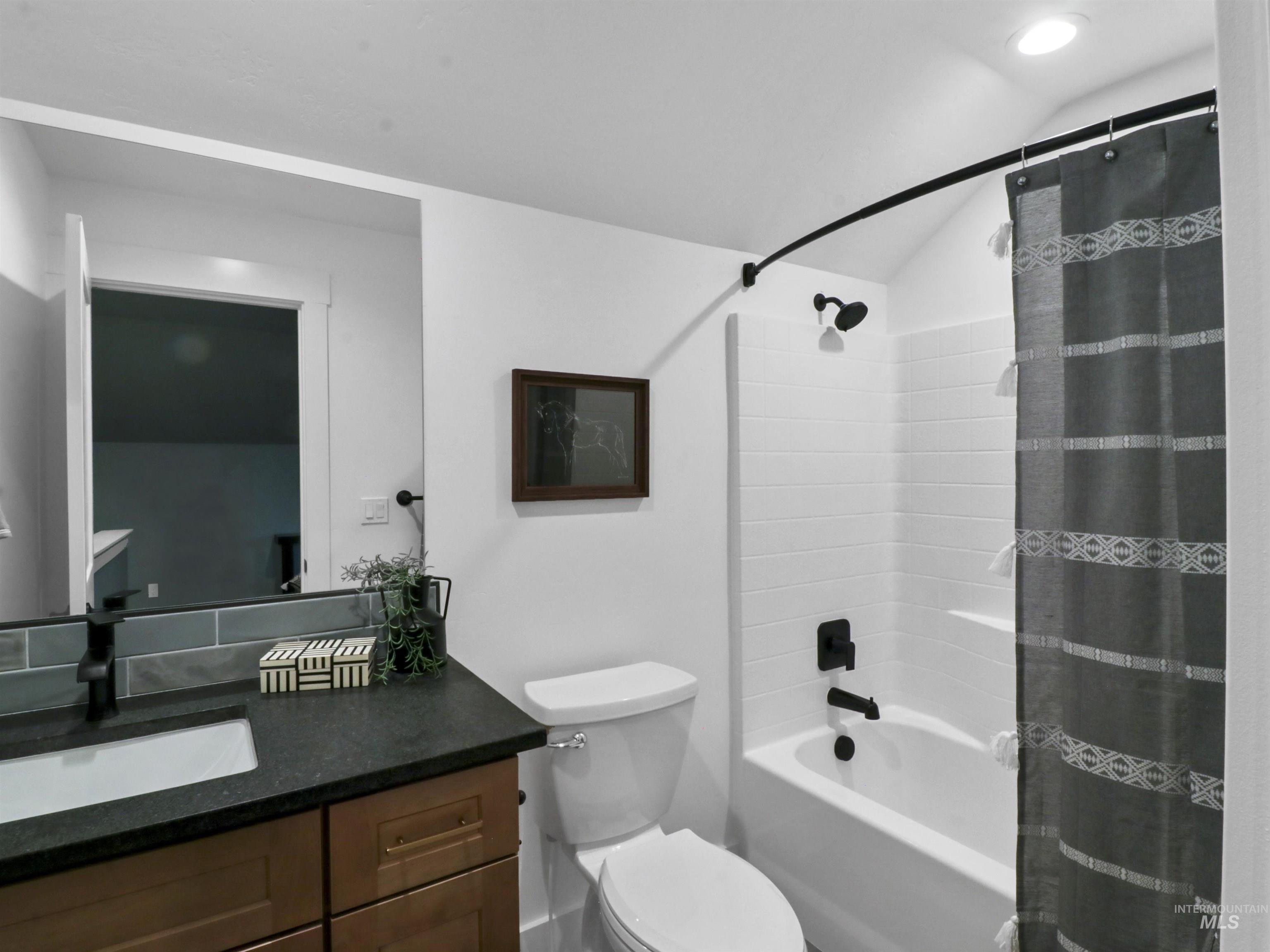 Bathroom with vanity, shower / bath combo, and vaulted ceiling
