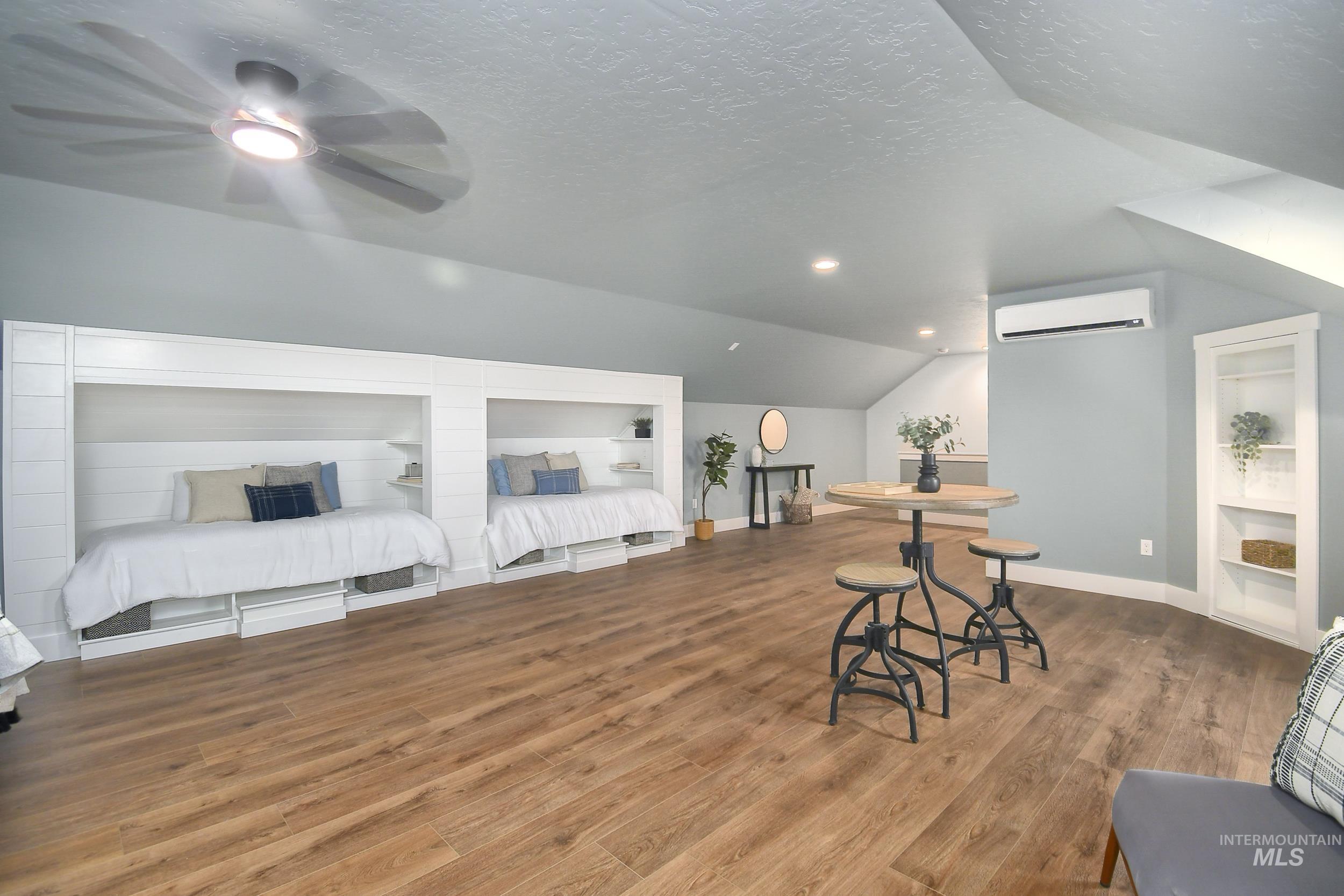 Bonus room featuring built in features, lofted ceiling, a textured ceiling, wood finished floors, and an AC wall unit