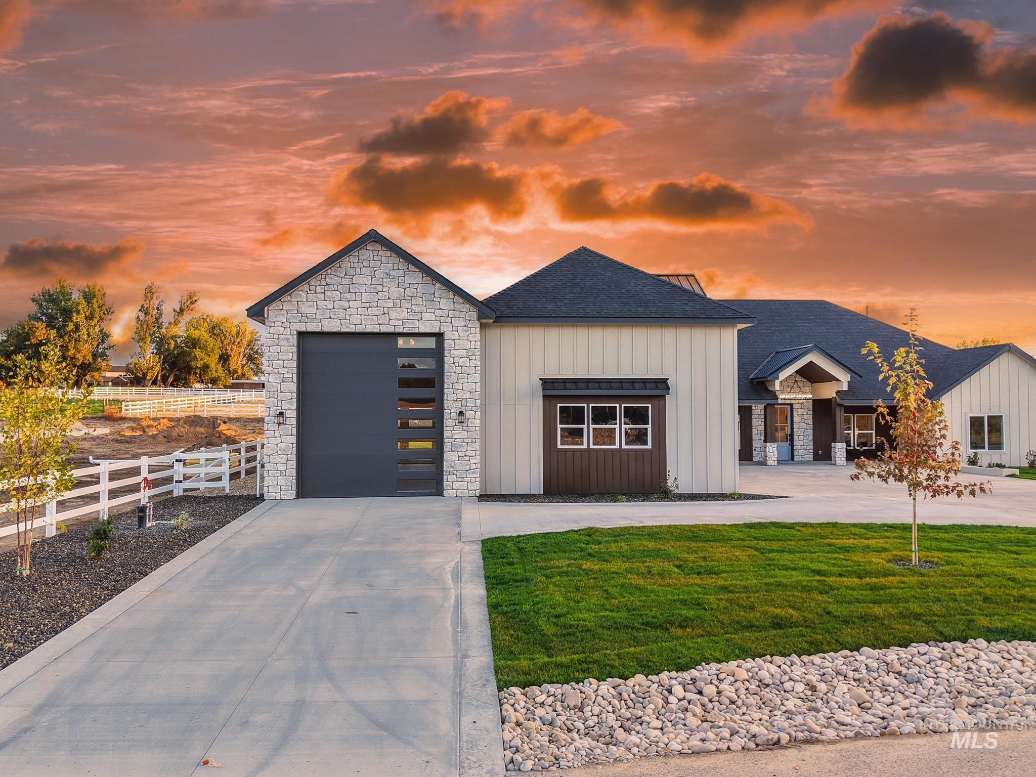 View of front facade with board and batten siding, concrete driveway, roof with shingles, and stone siding