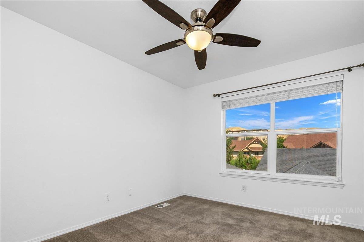 Spare room featuring dark colored carpet and baseboards