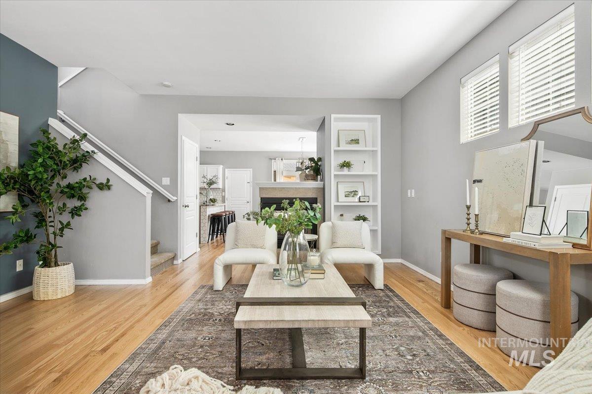 Living area with built in shelves, light wood-style floors, stairway, and a fireplace