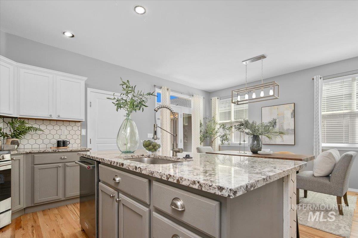 Kitchen featuring backsplash, gray cabinetry, light wood-type flooring, light stone counters, and recessed lighting