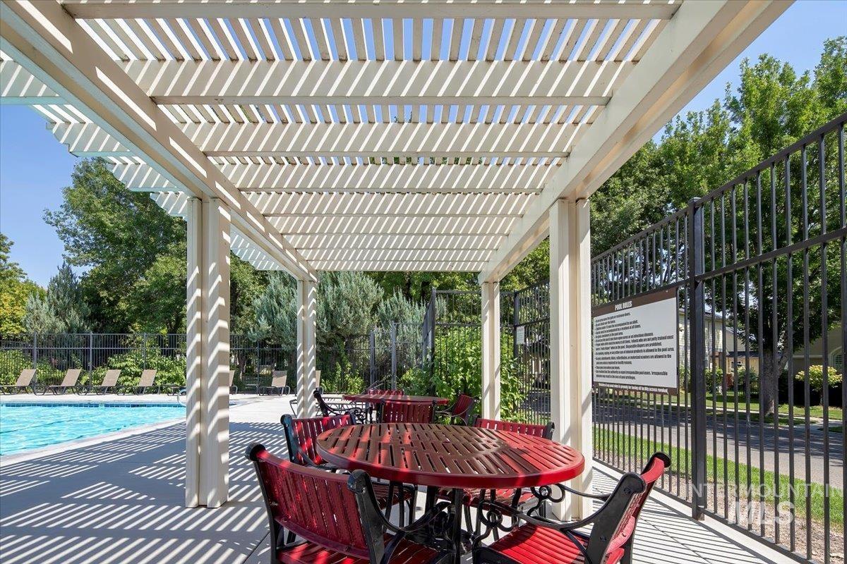 View of patio / terrace featuring a community pool, a pergola, outdoor dining area