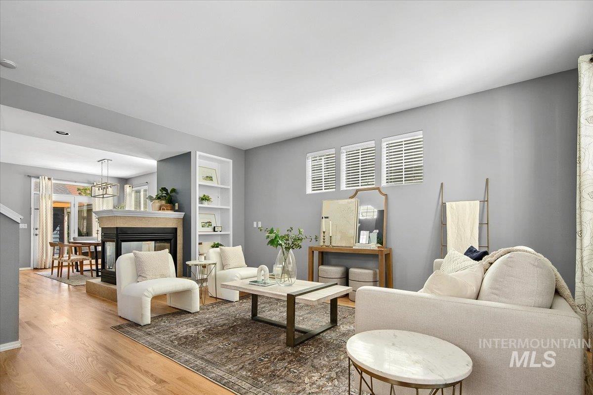 Living area with newly refinished wood finished floors, built in features, and a multi sided fireplace