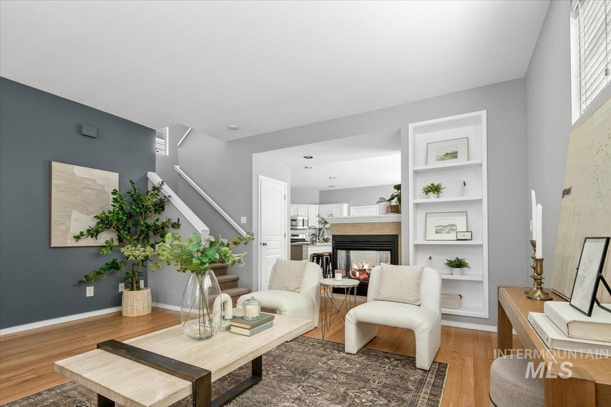 Living area featuring stairway, wood finished floors, a multi sided fireplace, and built in features