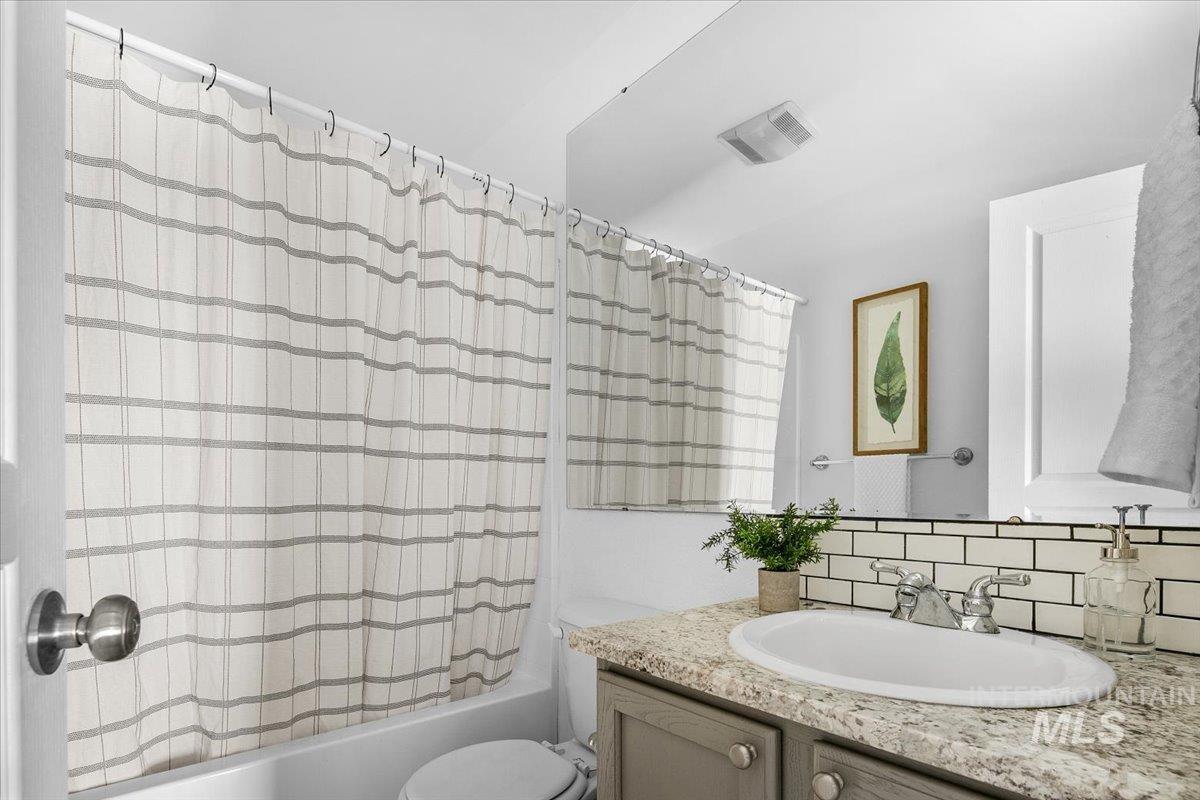 Bathroom with shower / tub combo, vanity, and backsplash
