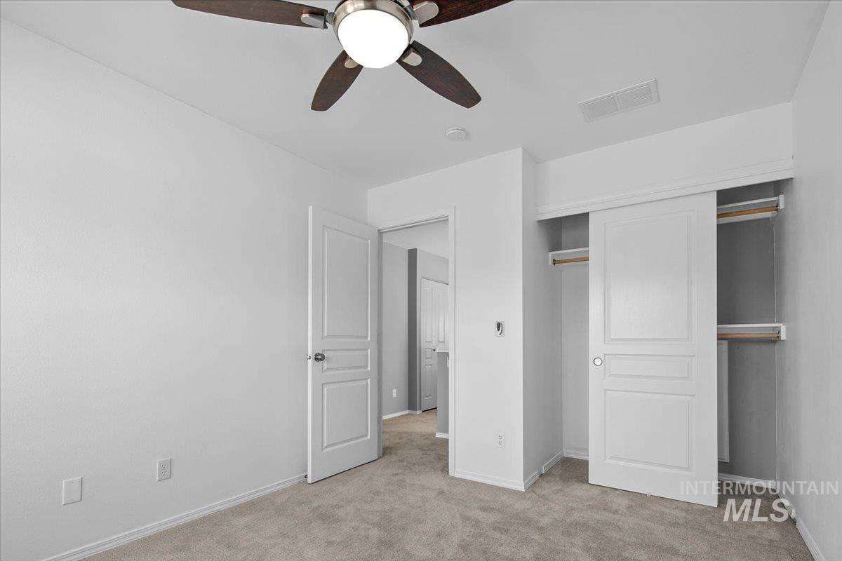 Unfurnished bedroom with light colored carpet, a closet, and a ceiling fan