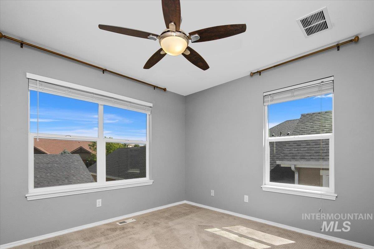 Unfurnished room with carpet, healthy amount of natural light, and ceiling fan