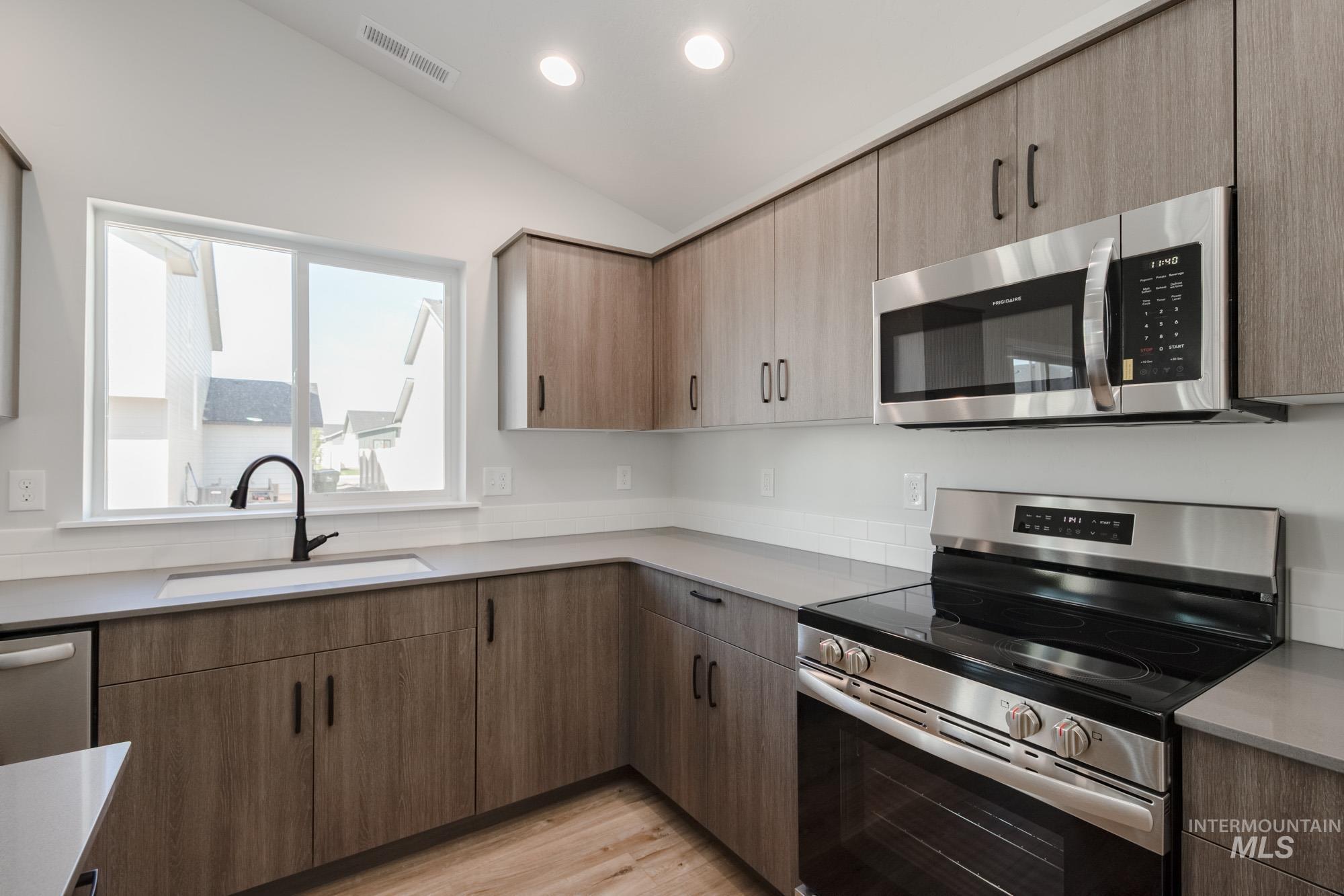Kitchen with stainless steel appliances, lofted ceiling, light wood-style flooring, recessed lighting, and modern cabinets