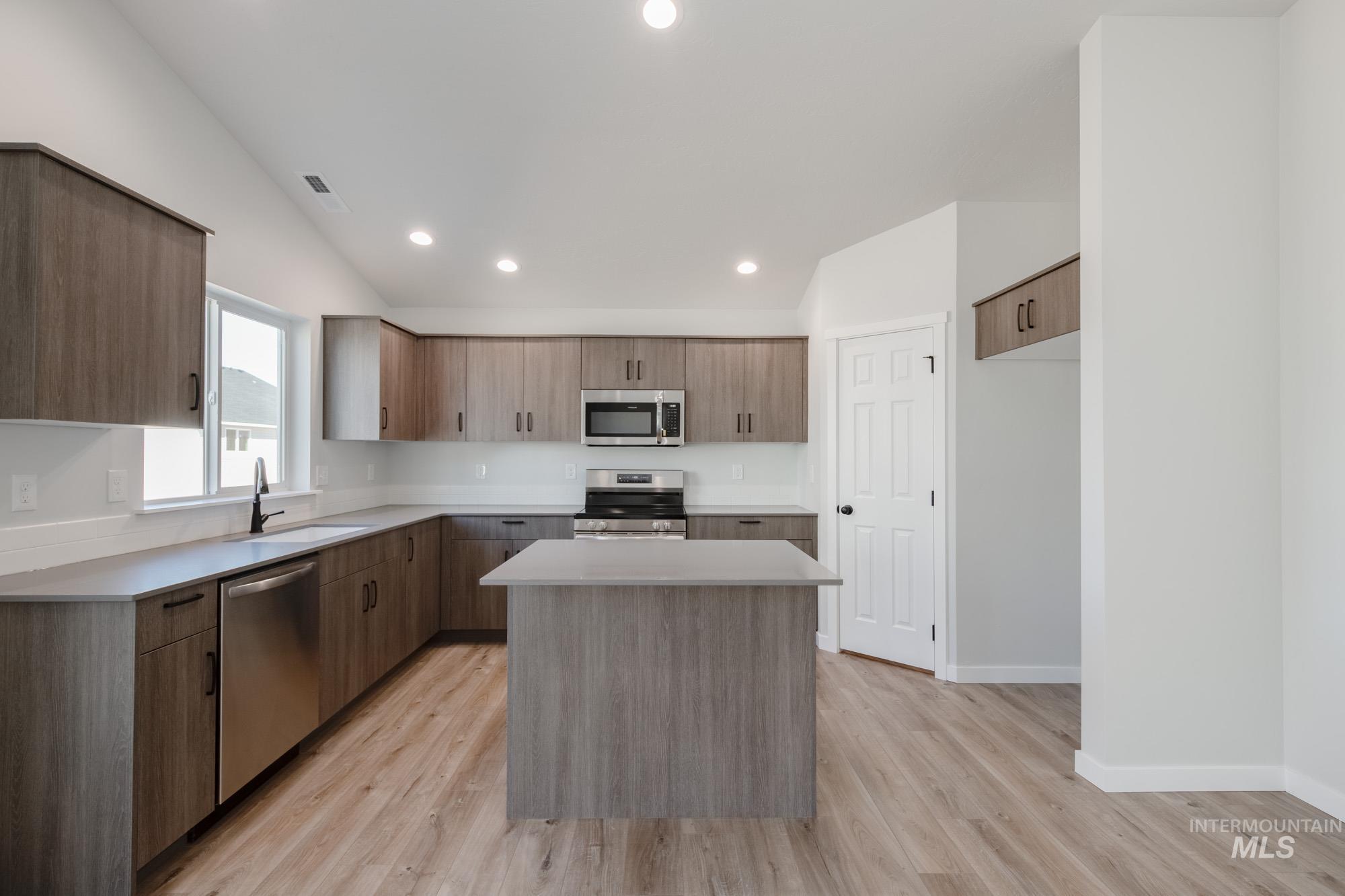Kitchen with modern cabinets, a kitchen island, appliances with stainless steel finishes, recessed lighting, and light wood-style flooring