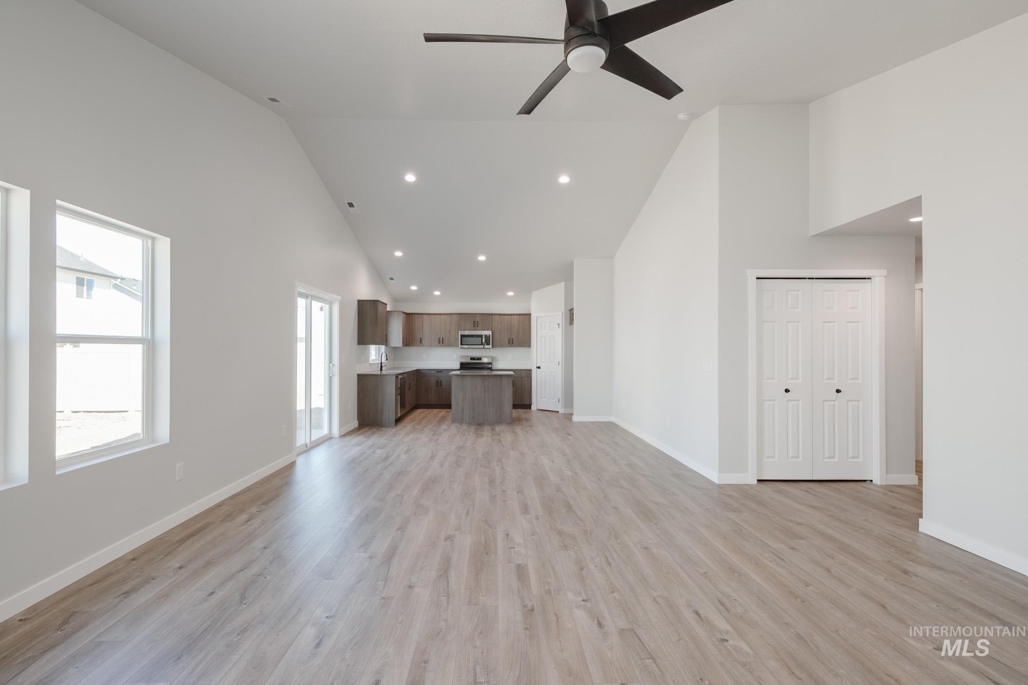 Unfurnished living room featuring high vaulted ceiling, recessed lighting, light wood finished floors, and ceiling fan