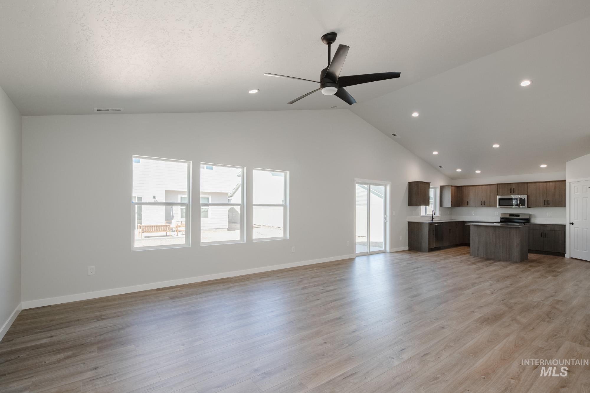 Unfurnished living room with light wood-type flooring, high vaulted ceiling, recessed lighting, and ceiling fan