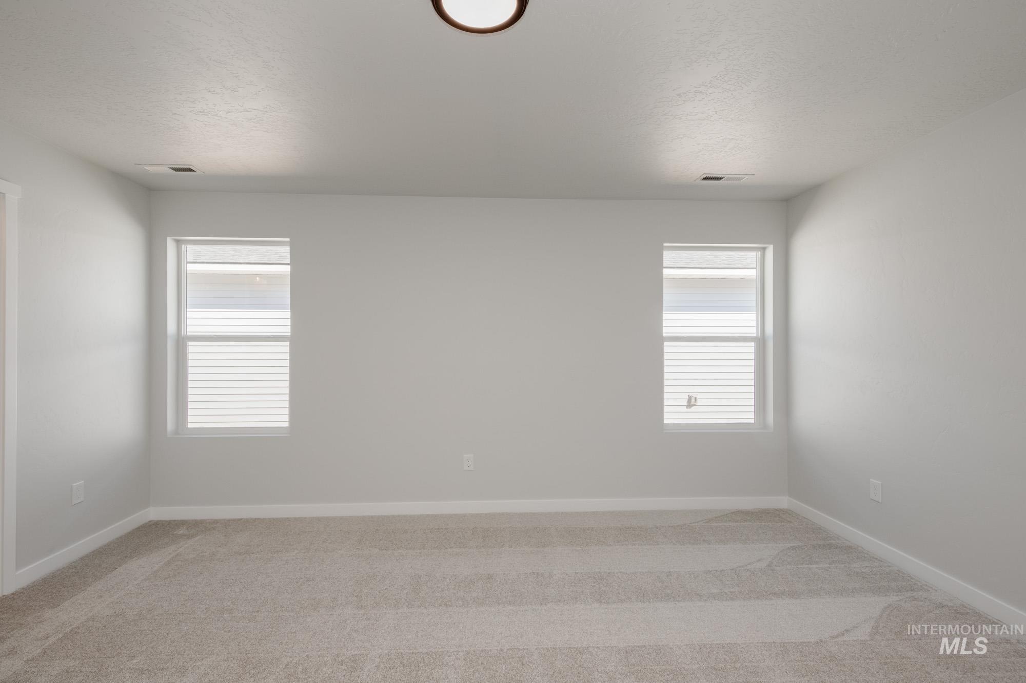 Empty room with light carpet and a textured ceiling