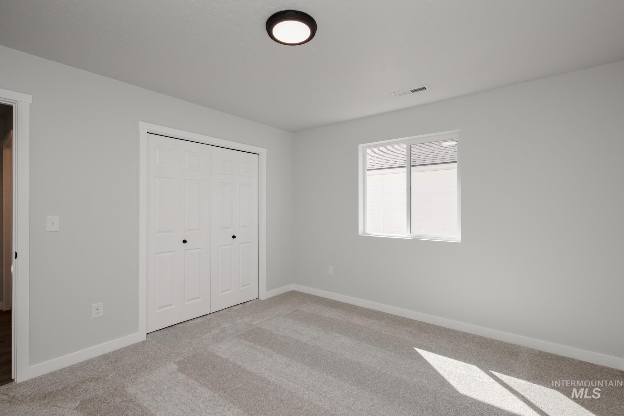 Unfurnished bedroom featuring light colored carpet and a closet